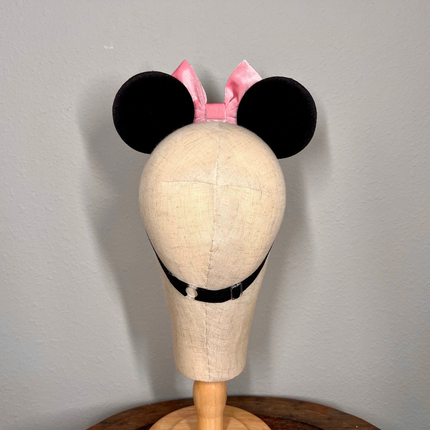 Mannequin head with black mouse ears and pink bow on a gray background