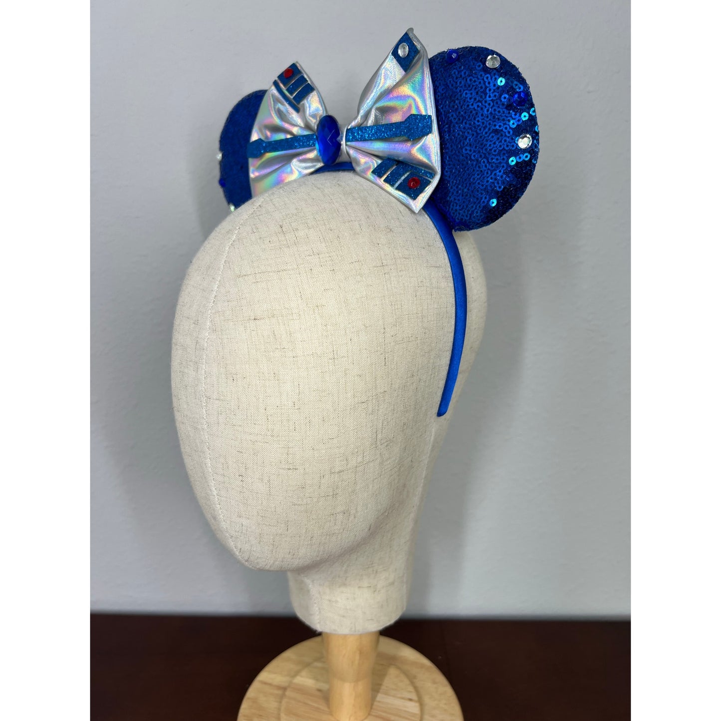 Blue and silver mouse ears headband with bow on a mannequin head against a gray background