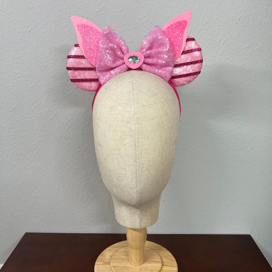 Pink mouse ears bow headband with striped sides on a mannequin head against a plain background