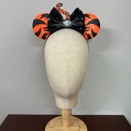 Orange mouse ears with black sequin bow, with black tiger stripes, black glitter whiskers, rhinestone nose, and orange and black tiger tail centerpiece on a mannequin head