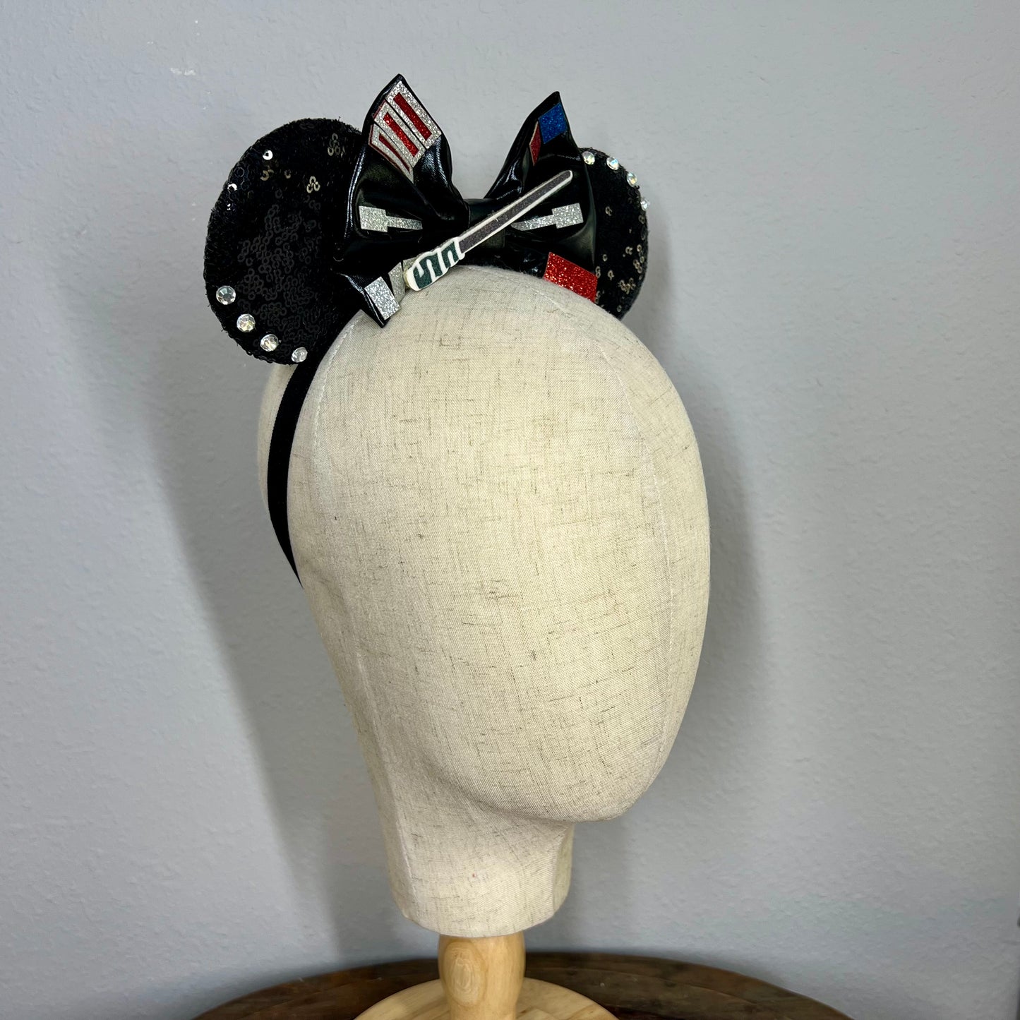 Black mouse ears headband with black fabric bow, saber detail, and decorative silver, red, and blue accents (side view)