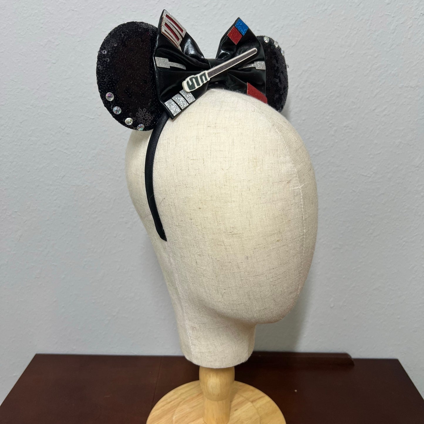 Black headband with decorative elements on a mannequin head against a plain background