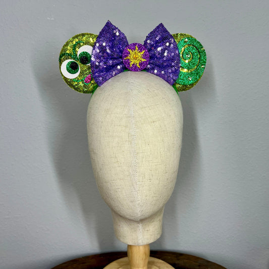 Decorative mouse ears headband with purple and green accents on a mannequin head against a gray background