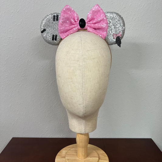Mannequin head wearing silver and pink sequin mouse ears against a plain background