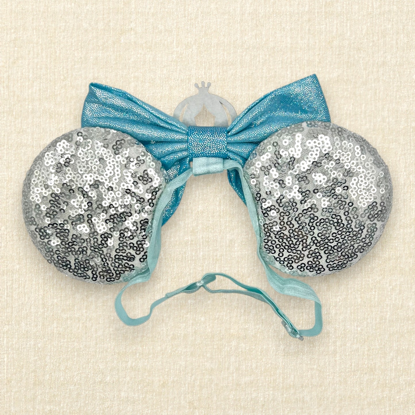 Silver sequin mouse ears on an elastic headband with shimmery blue bow and silver glitter carriage accent and rhinestones