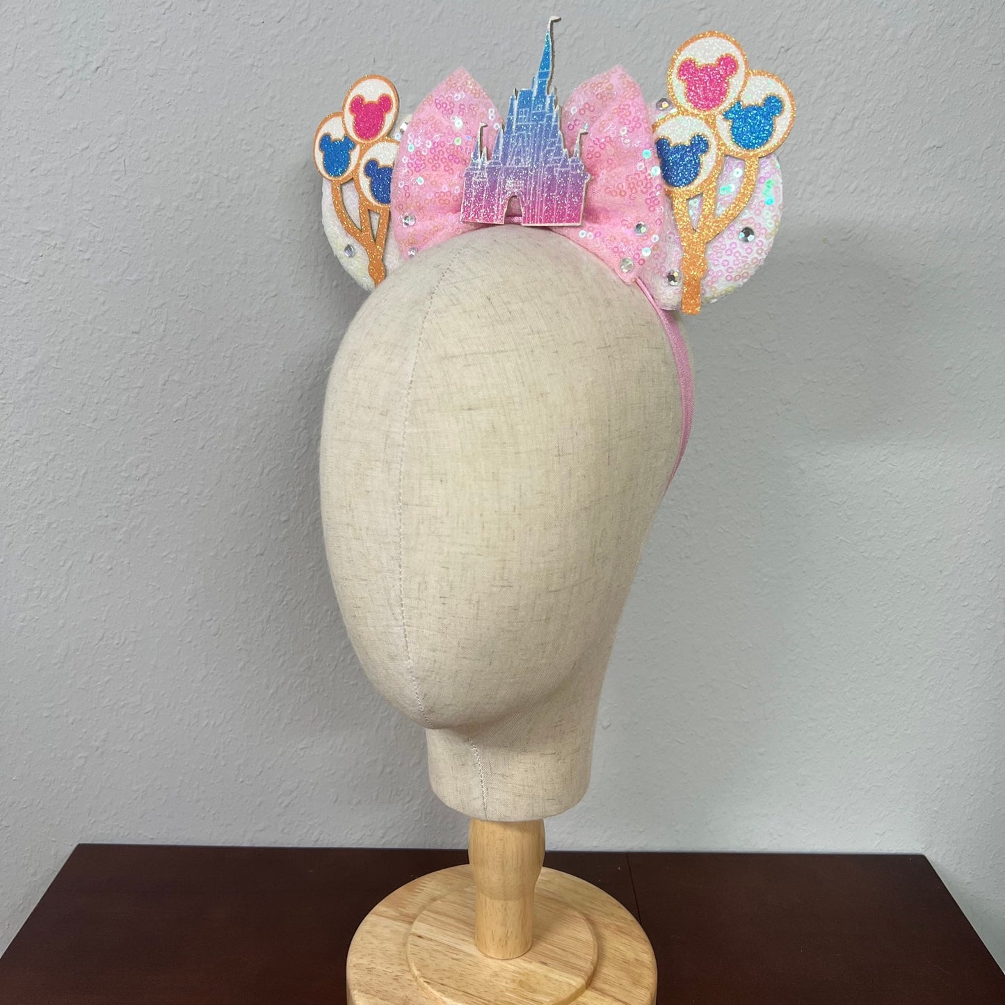 Decorative headband with castle and balloons design on a mannequin head against a plain background