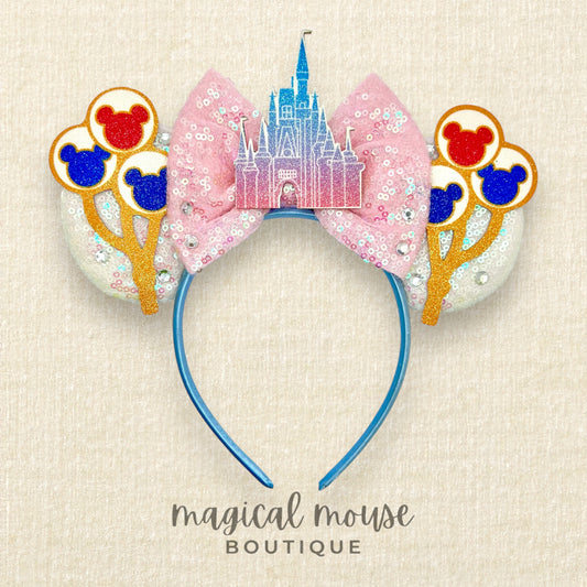 Disney-themed headband with castle design and balloons on a beige background
