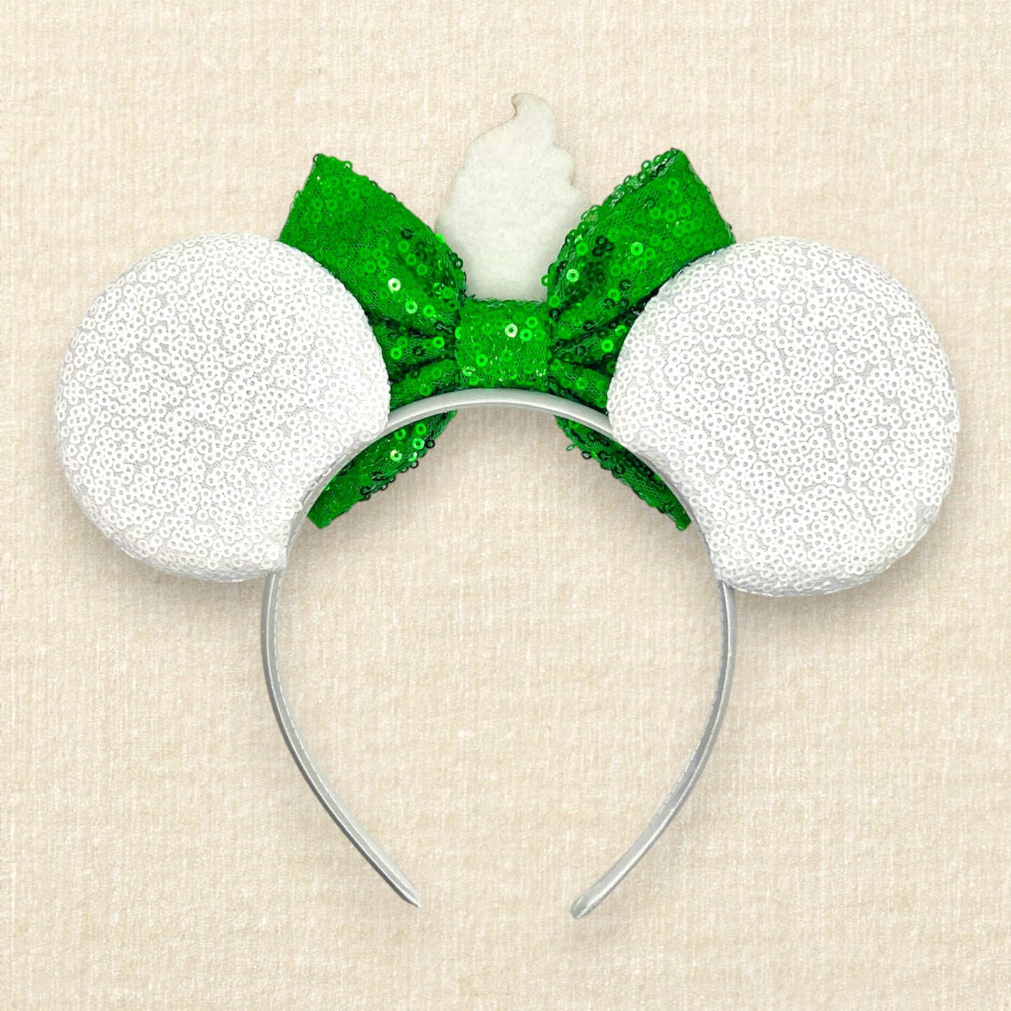 White mouse ears with glitter pineapple rings, green bow, and cup of pineapple swirl soft serve