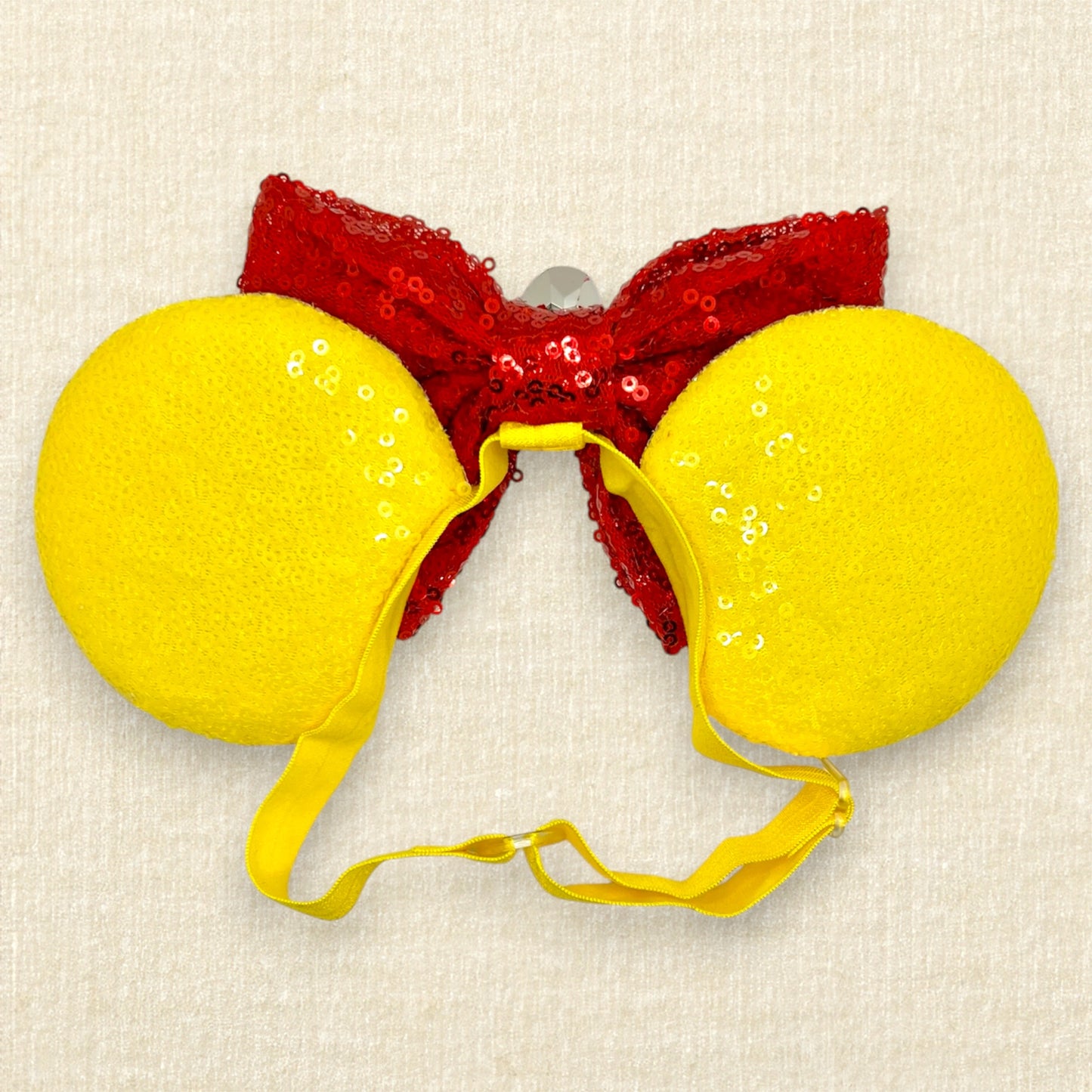 Yellow sequin mouse ears with glitter honey and bee accents, red sequin bow, wooden honey dipper, and yellow rhinestone on an elastic headband (back view)