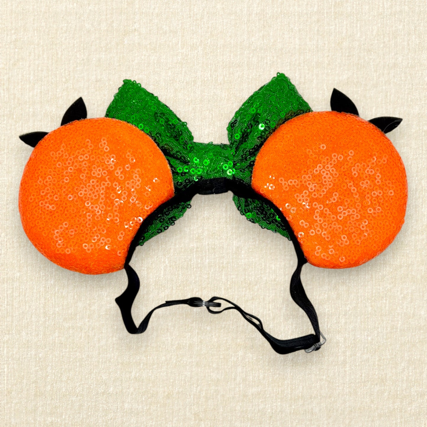 Orange mouse ears on an elastic headband with green sequin bow and glitter bird details
