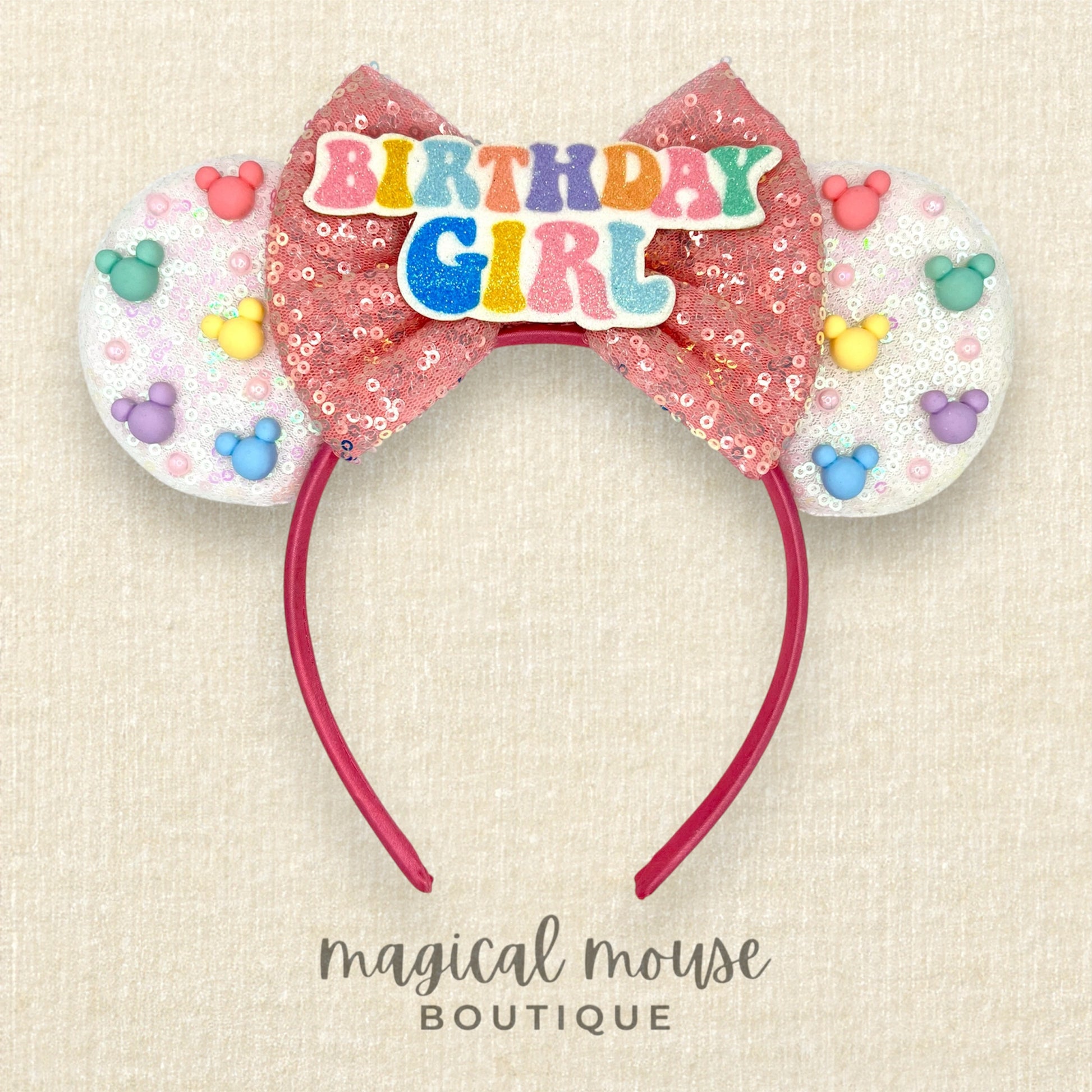 White sequin headband with pink bow, rainbow mouse-shaped pearls, and glitter "Birthday Girl" text centerpiece
