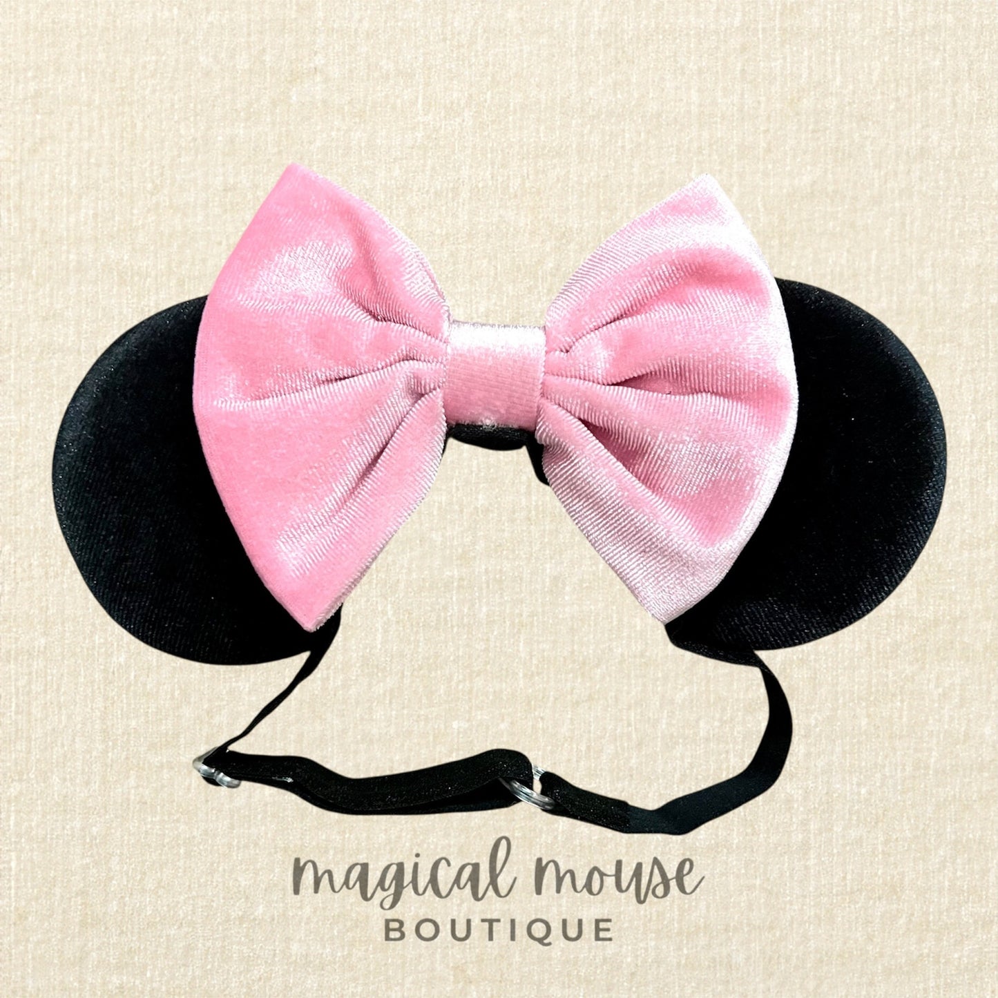 Pink velvet bow with black mouse ears on a beige background, branded 'magical mouse boutique'.