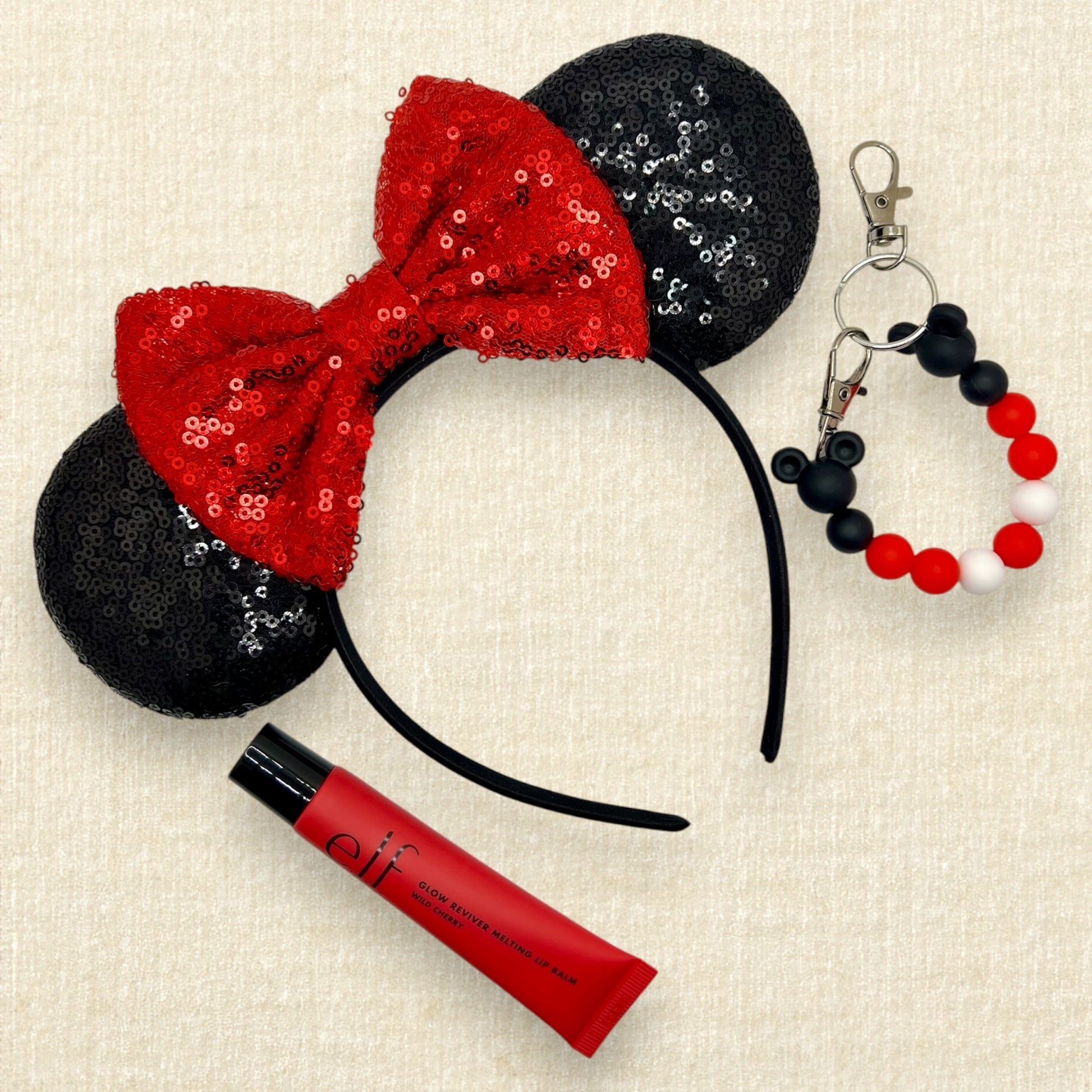 Black sequin mouse ears with red sequin bow; tube of lip balm; black and red beaded mouse ears holder keychain
