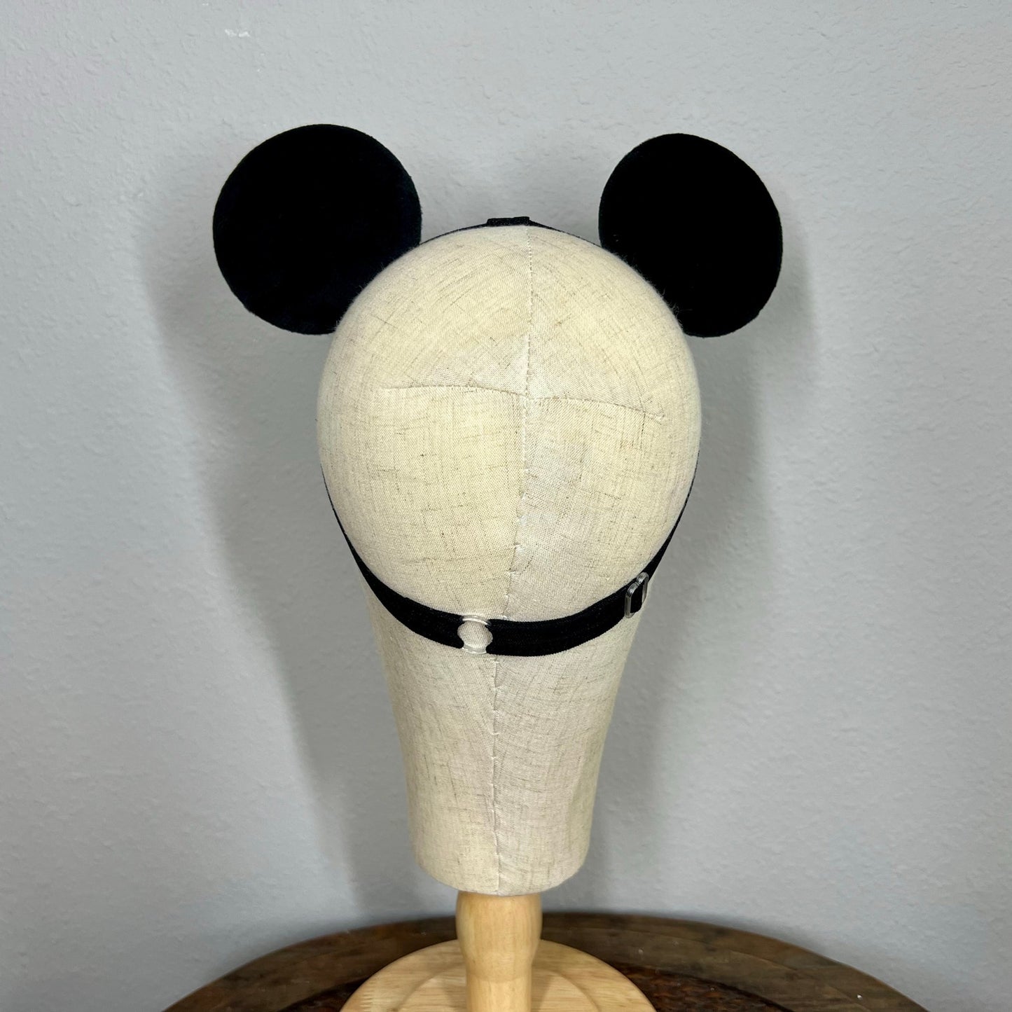 Mannequin head with black mouse ears on a plain background
