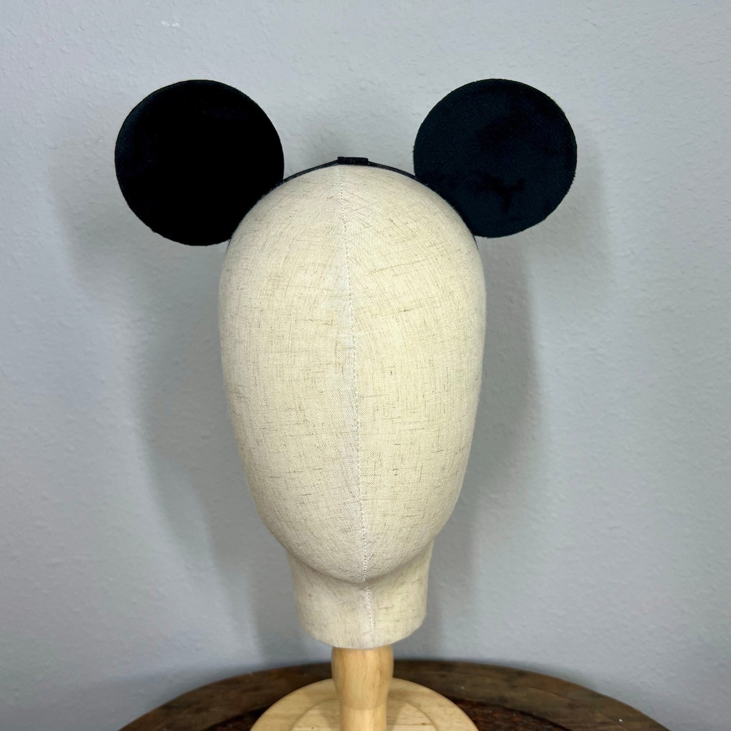 Black mouse ears on a mannequin head against a plain background