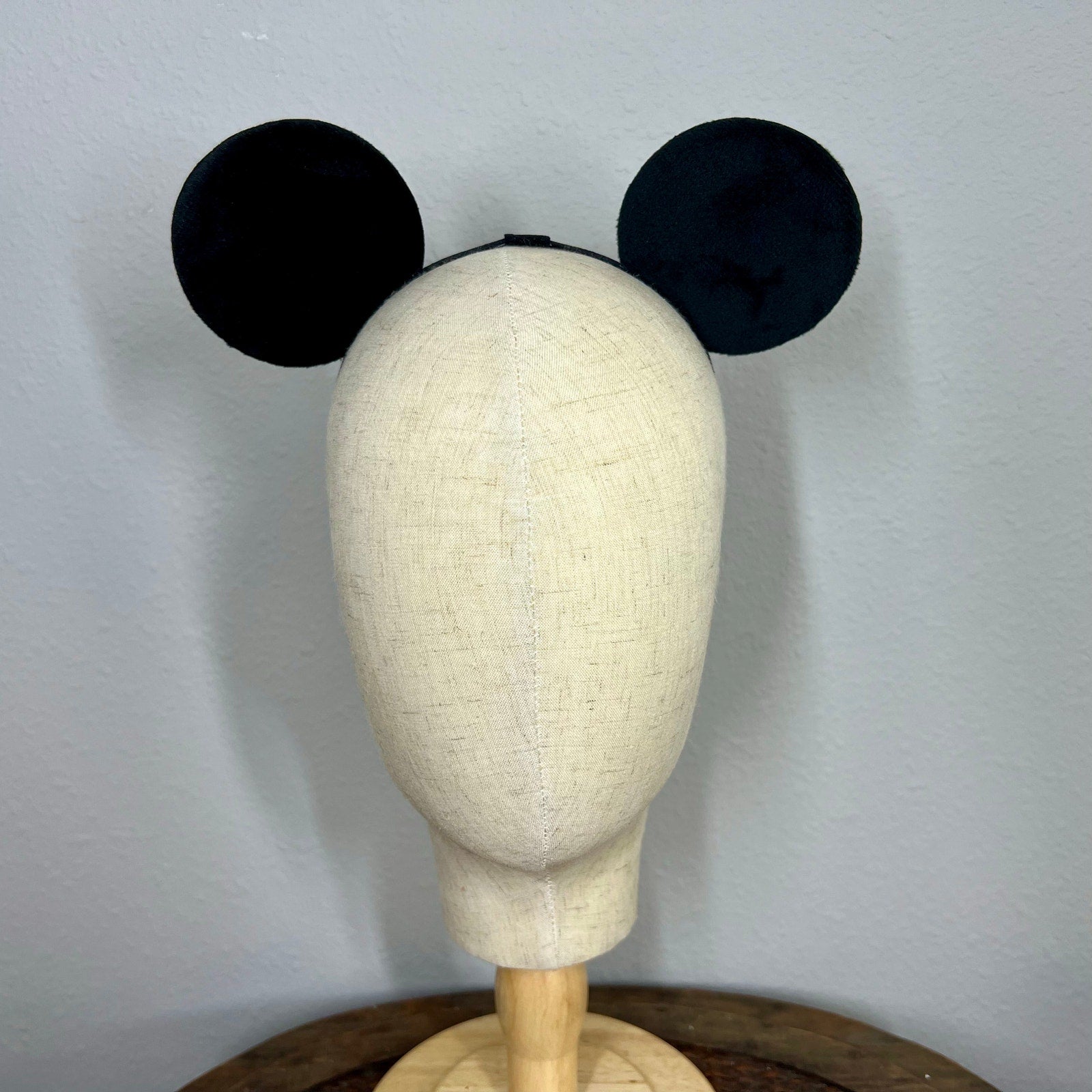 Black mouse ears on a mannequin head against a plain background