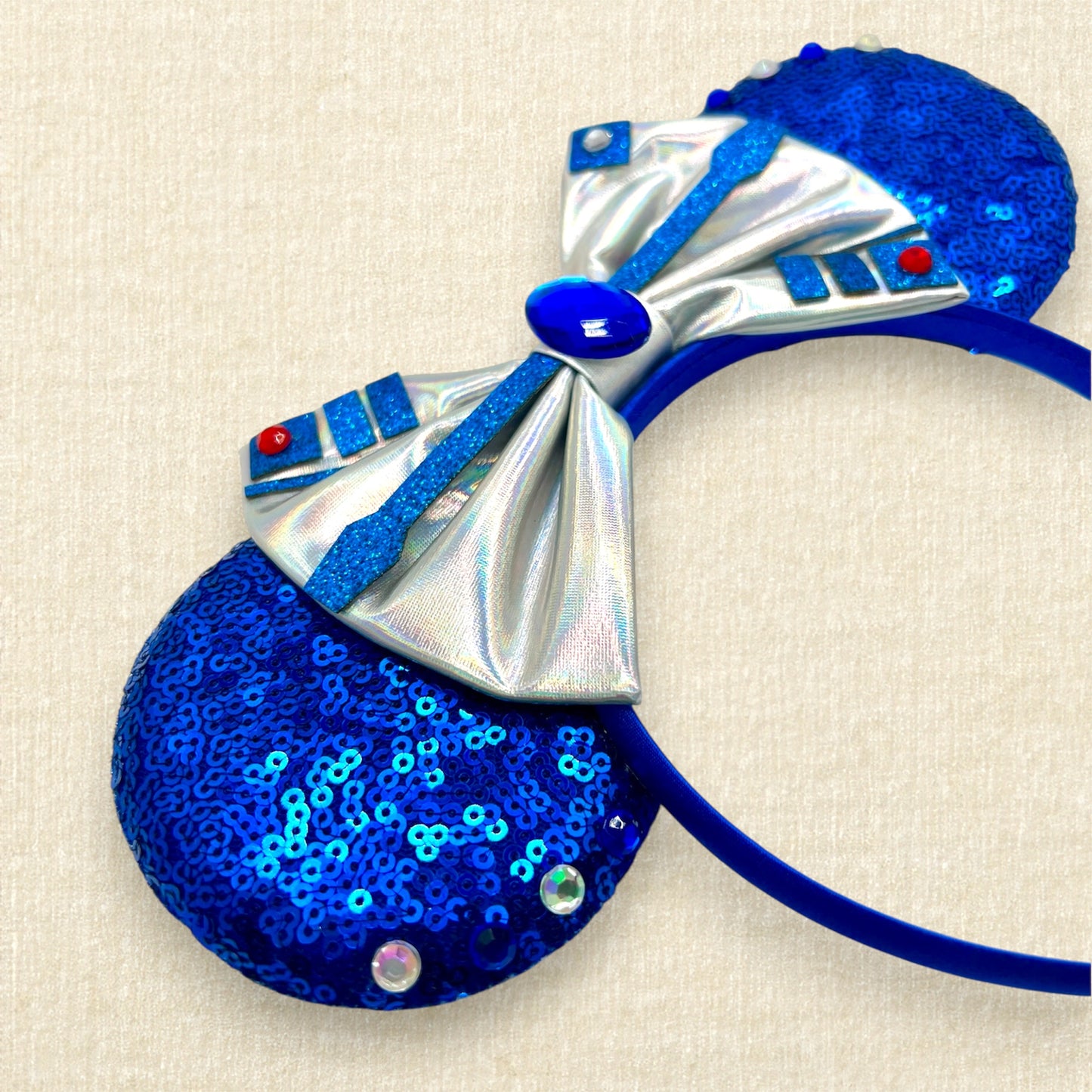 Detail view of mouse ears with metallic silver bow, rhinestones, and glitter robot-inspired details