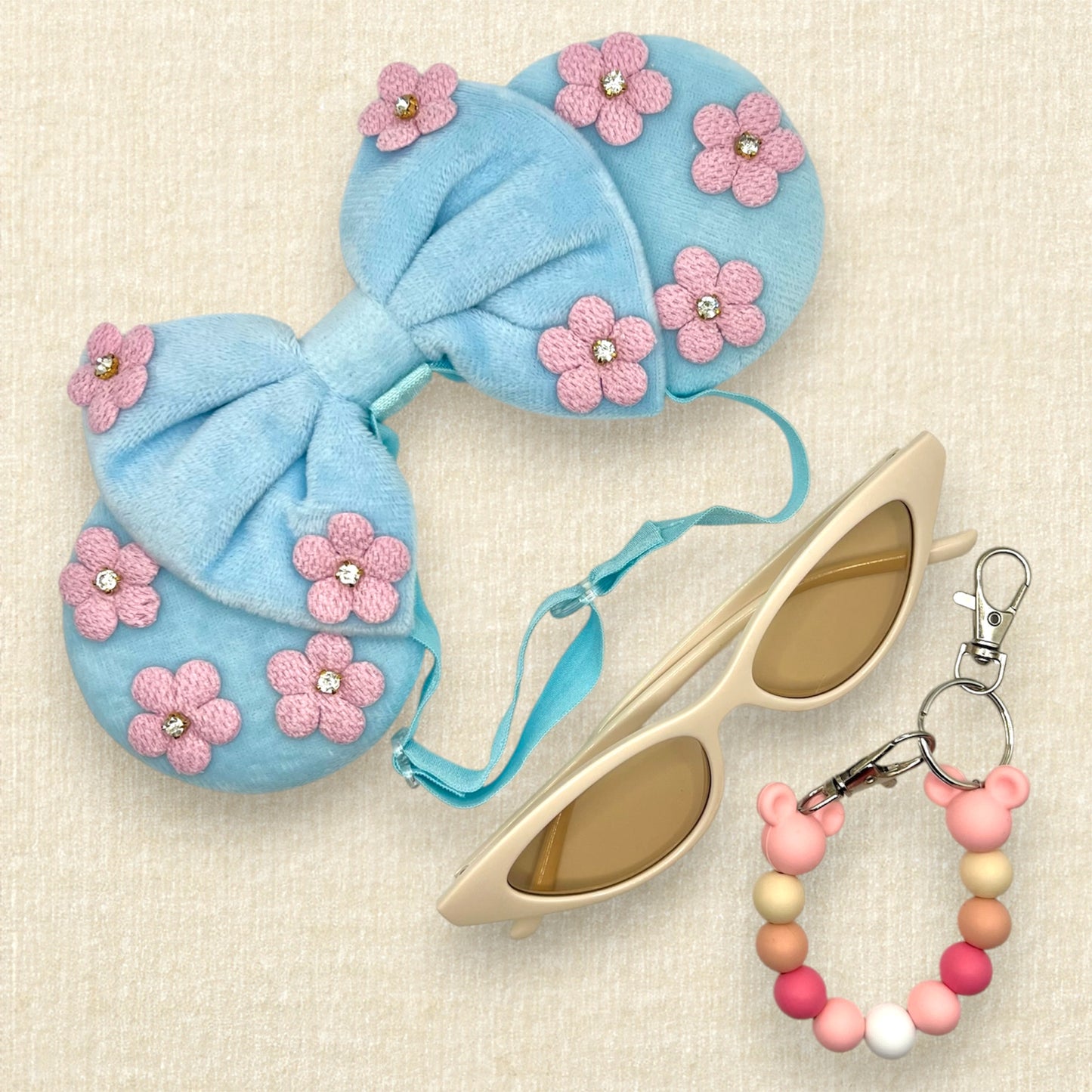 Blue velvet mouse ears and bow with pink fabric flowers on an elastic headband; cream cat-eye sunglasses; pink beaded mouse ears holder clip