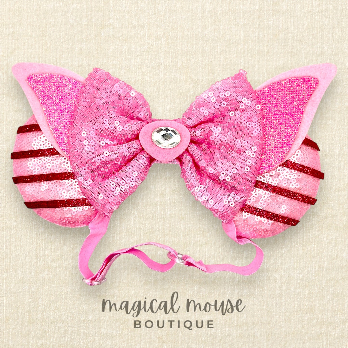 Pink sequin mouse ears with bow on beige background, branded 'magical mouse boutique'