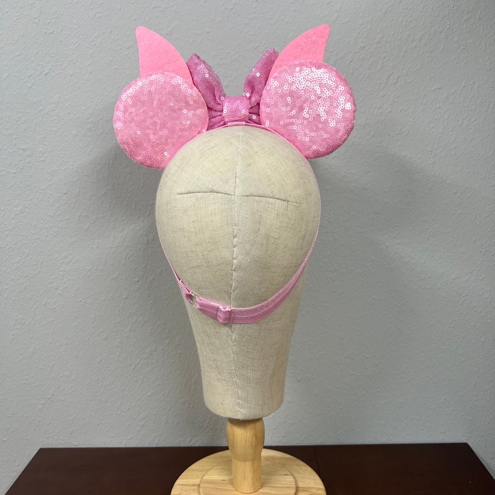 Pink sequin mouse ears with bow on a mannequin head