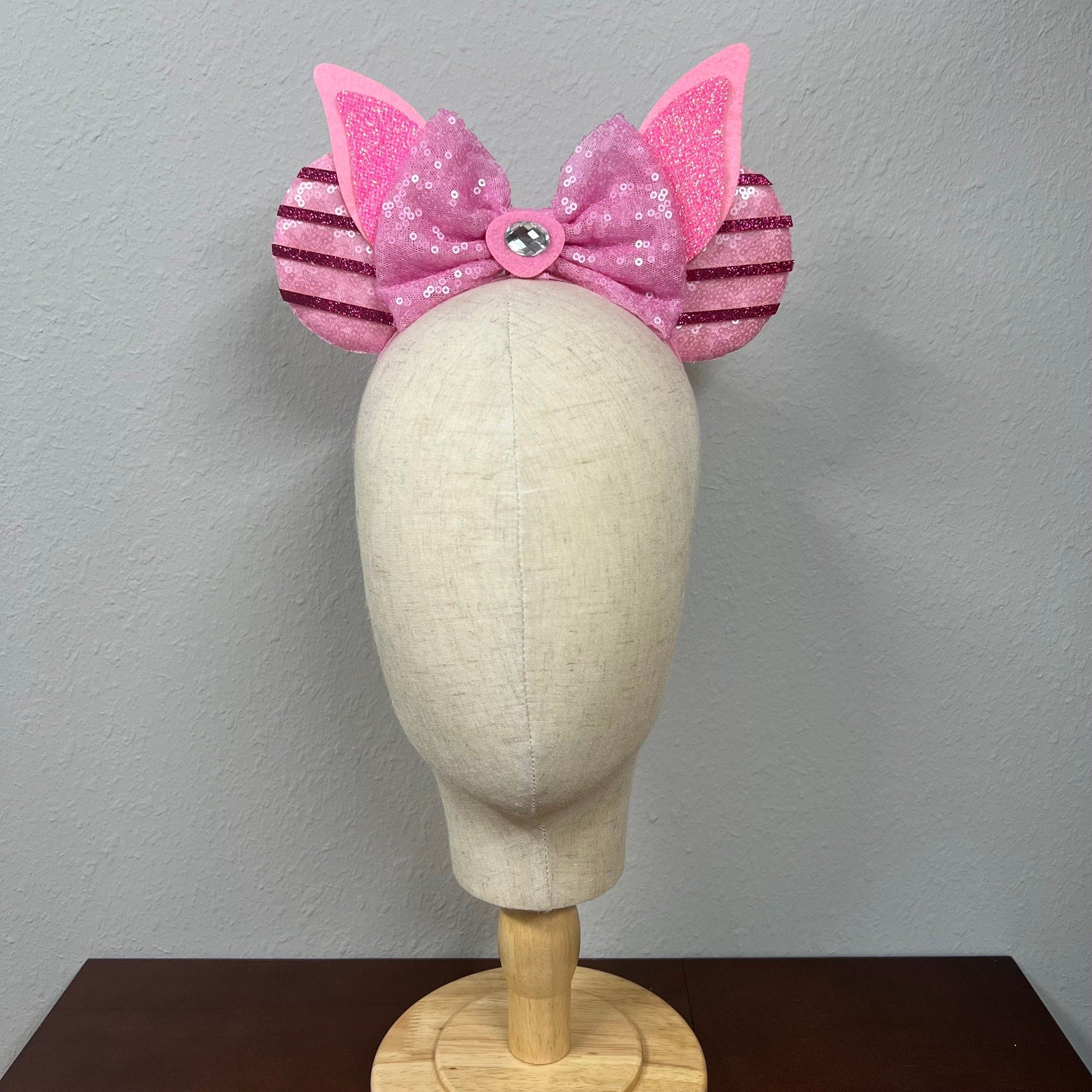 Pink sequin mouse ears with bow on a mannequin head