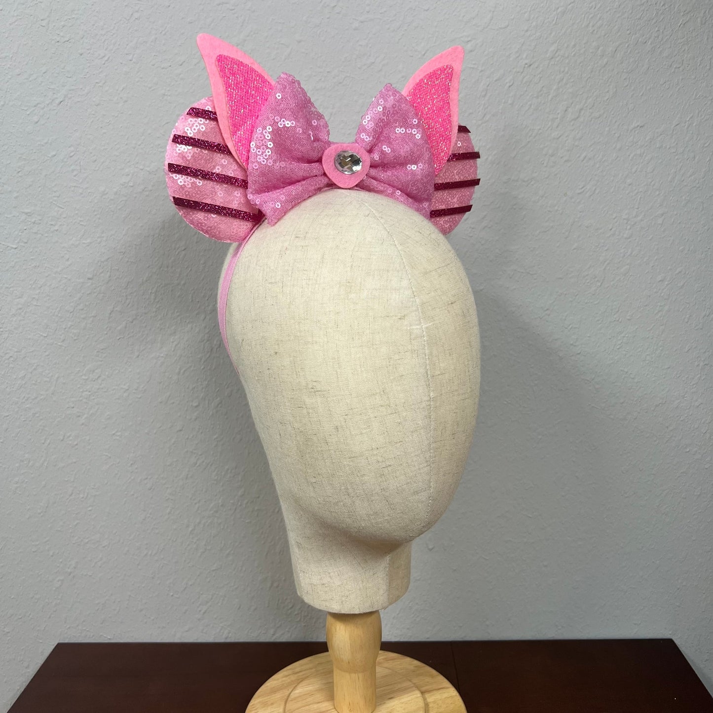 Pink sequin mouse ears with bow on a mannequin head