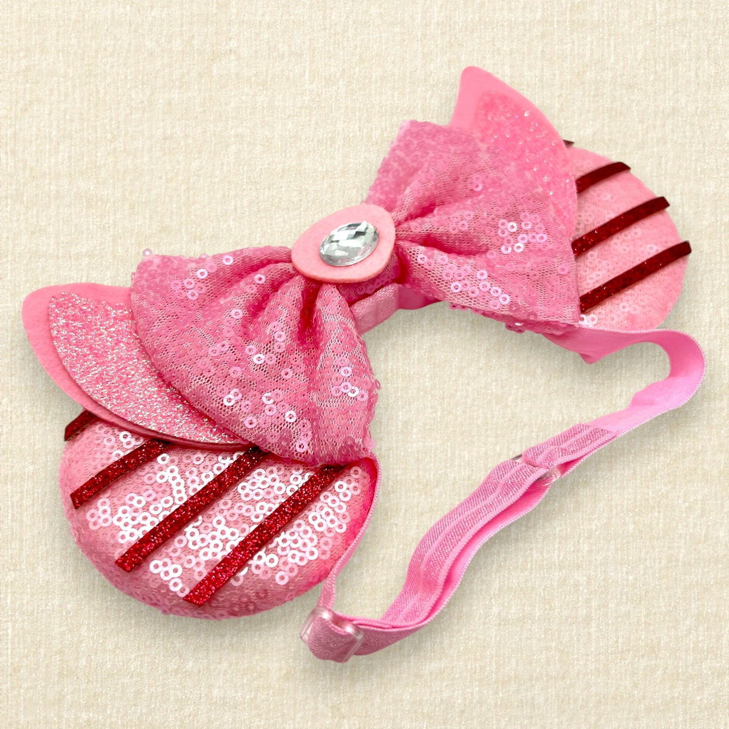 Pink sequin mouse ears with dark pink glitter stripes, pink sequin bow, and glitter piglet ears and nose detail on an elastic headband