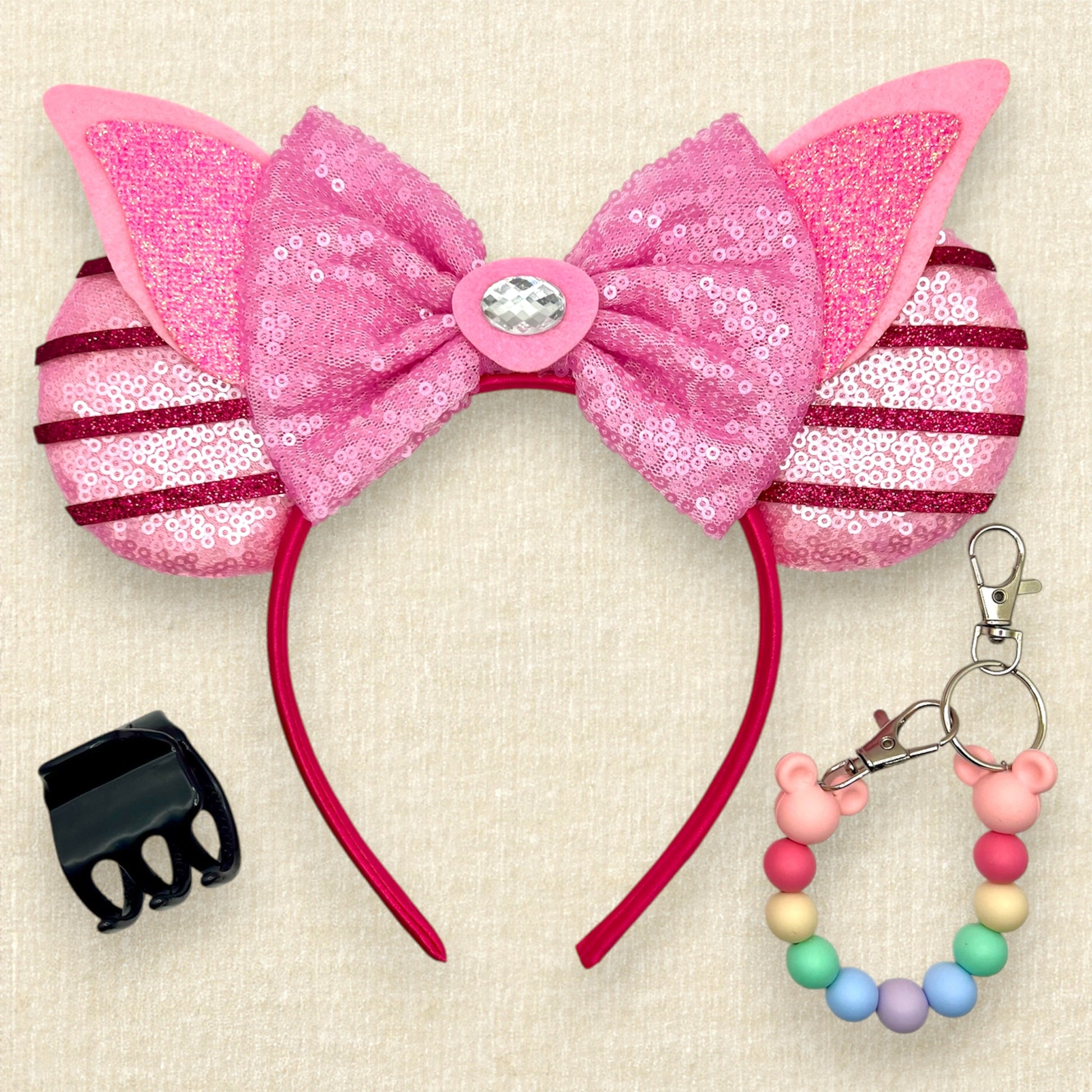 Pink sequin mouse ears with dark pink glitter stripes, pink sequin bow, pink glitter piglet ears, and rhinestone pig nose; black claw clip