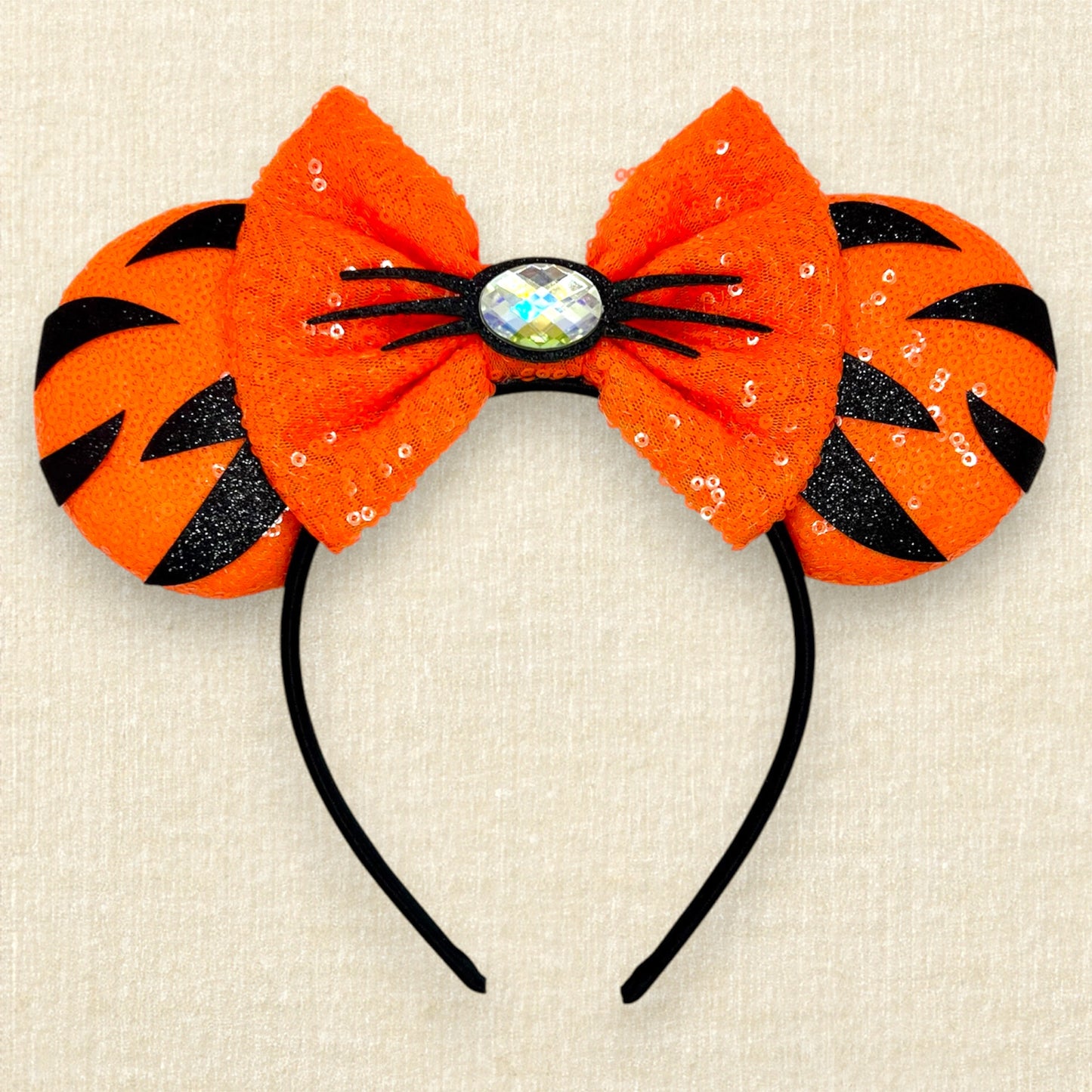 Orange sequin mouse ears headband with matching bow, black glitter tiger stripes, and rhinestone nose with black glitter whiskers