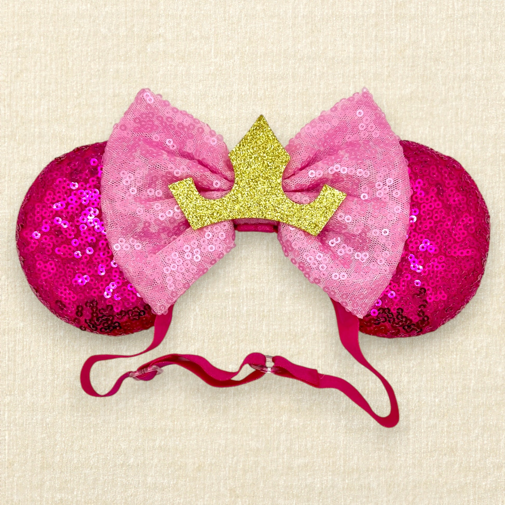 Hot pink sequin mouse ears with light pink sequin bow and gold crown on an elastic headband
