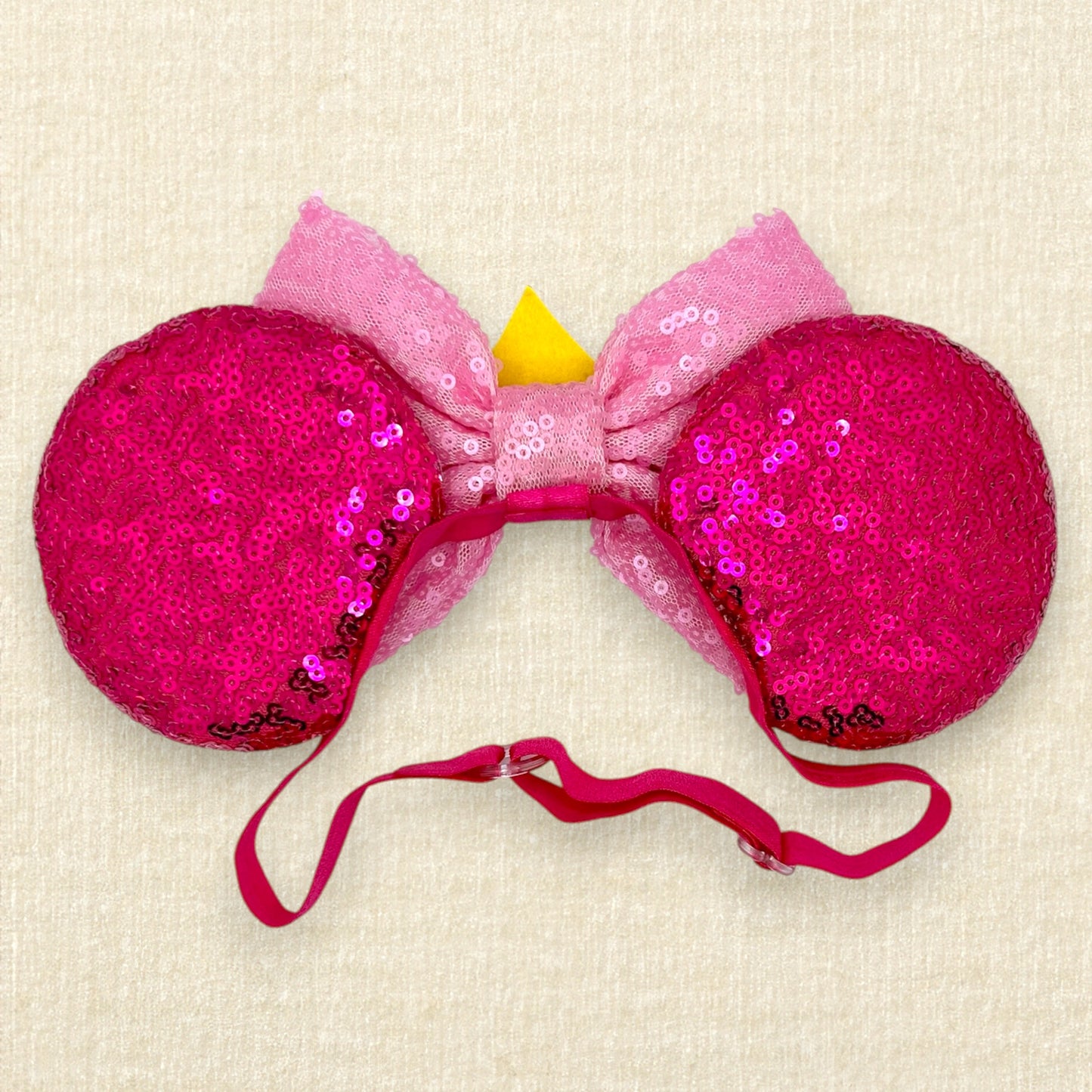 Hot pink sequin mouse ears with light pink sequin bow and gold crown on an elastic headband (back view)