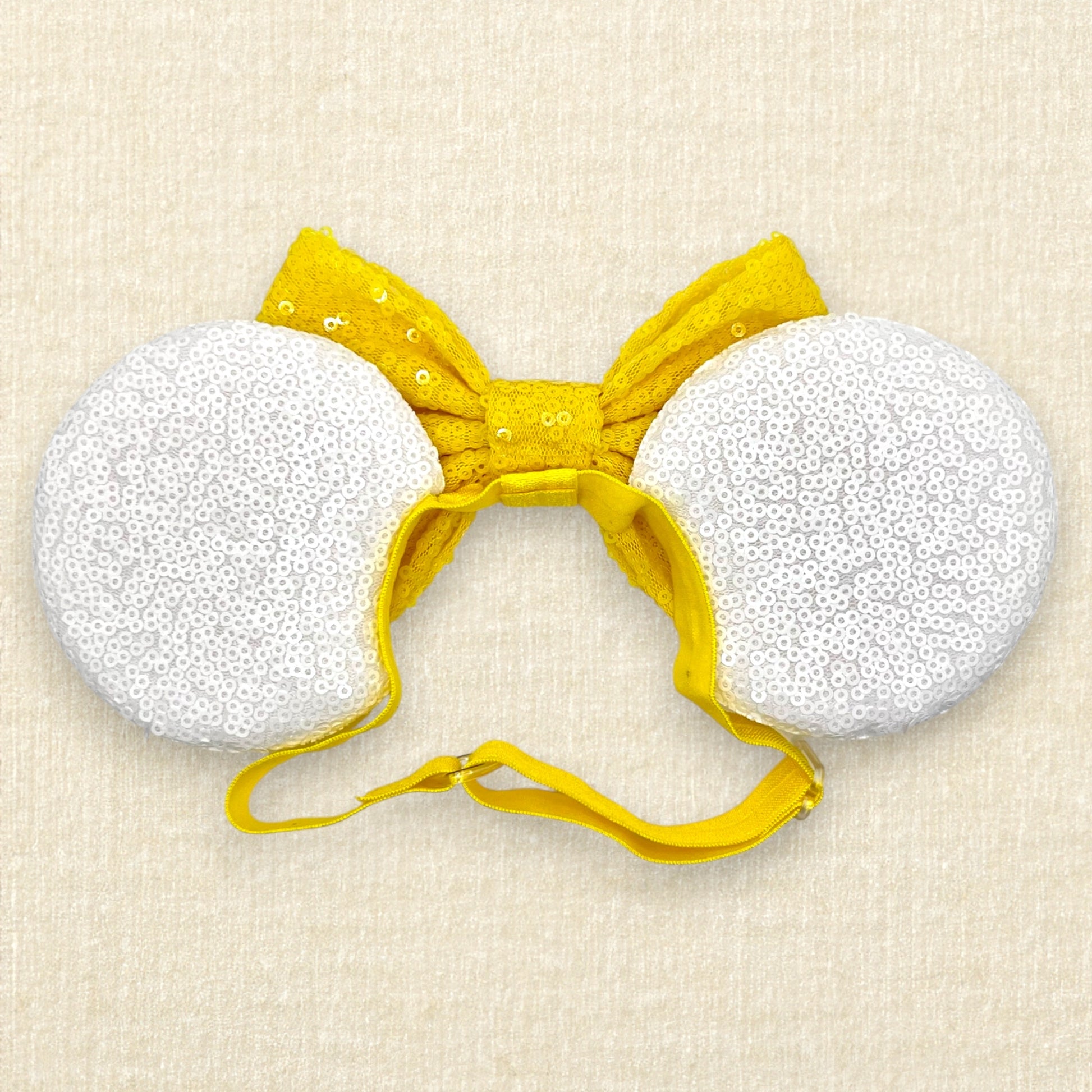 Halloween-themed mouse ears with white sequin ears, candy corn pieces, rhinestones, and yellow sequin bow on an elastic headband (back view)