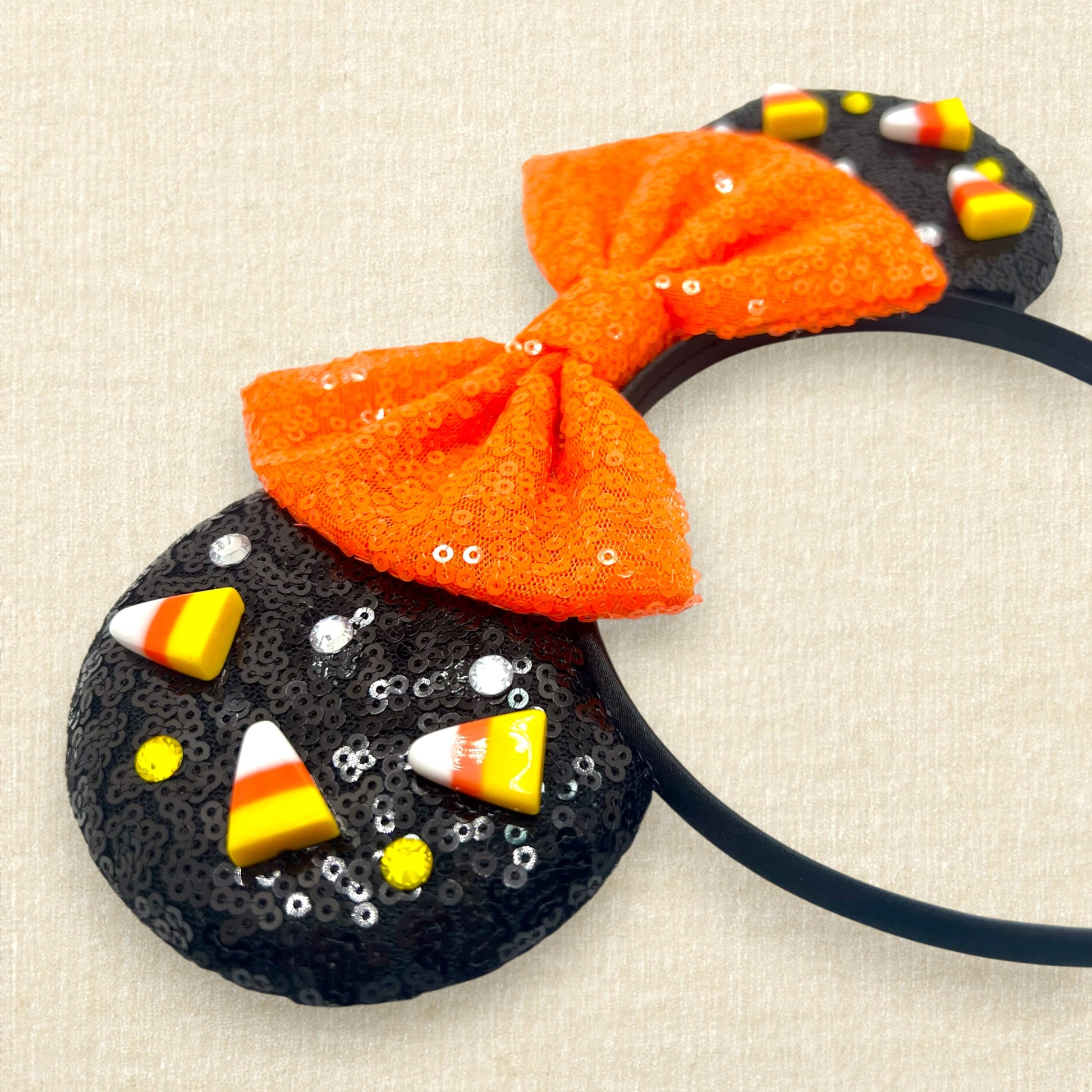 Black sequin Halloween-themed mouse ears with candy corn pieces, rhinestones, and orange sequin bow