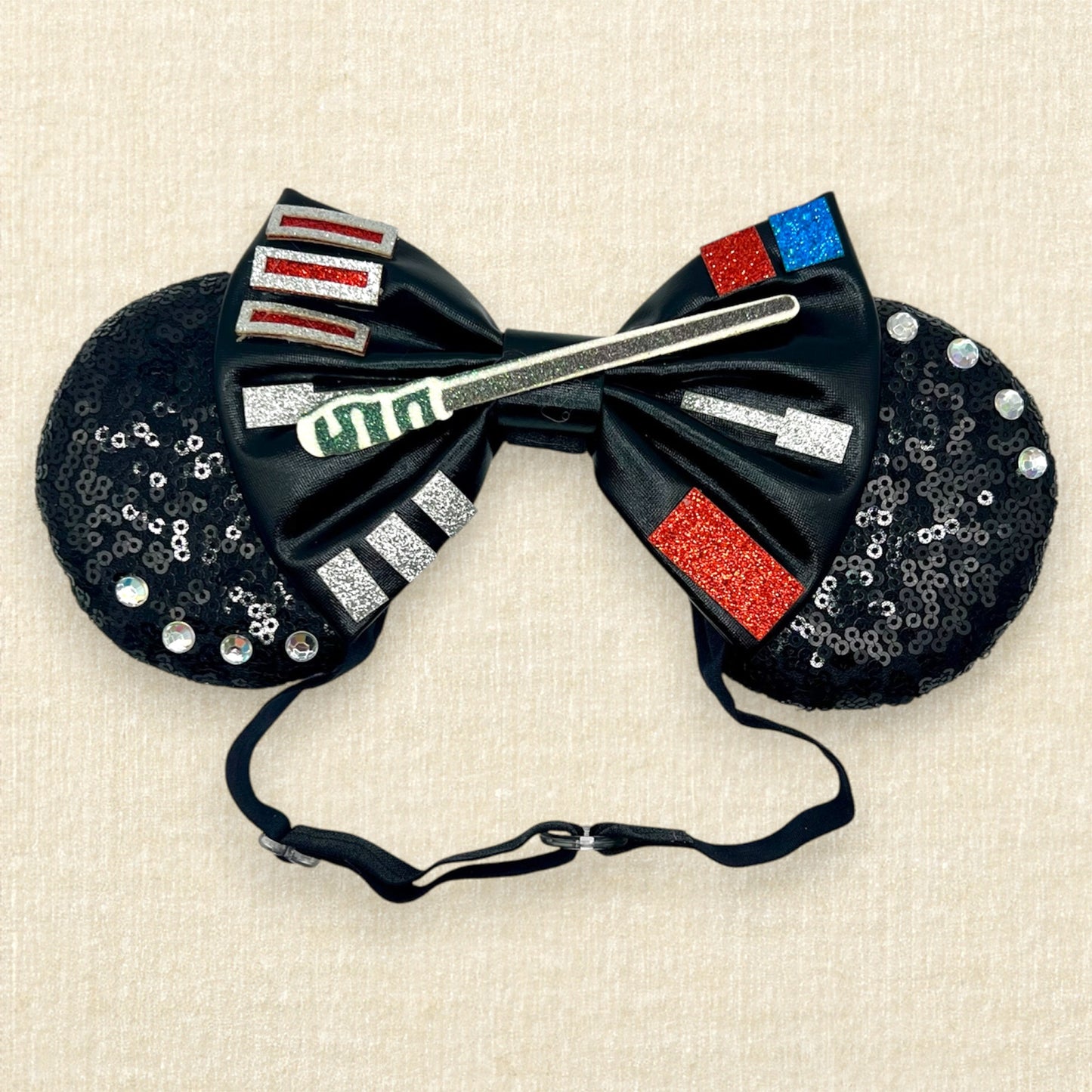 Black sequin mouse ears headband with metallic black bow, colorful glitter details, and rhinestones on an elastic headband