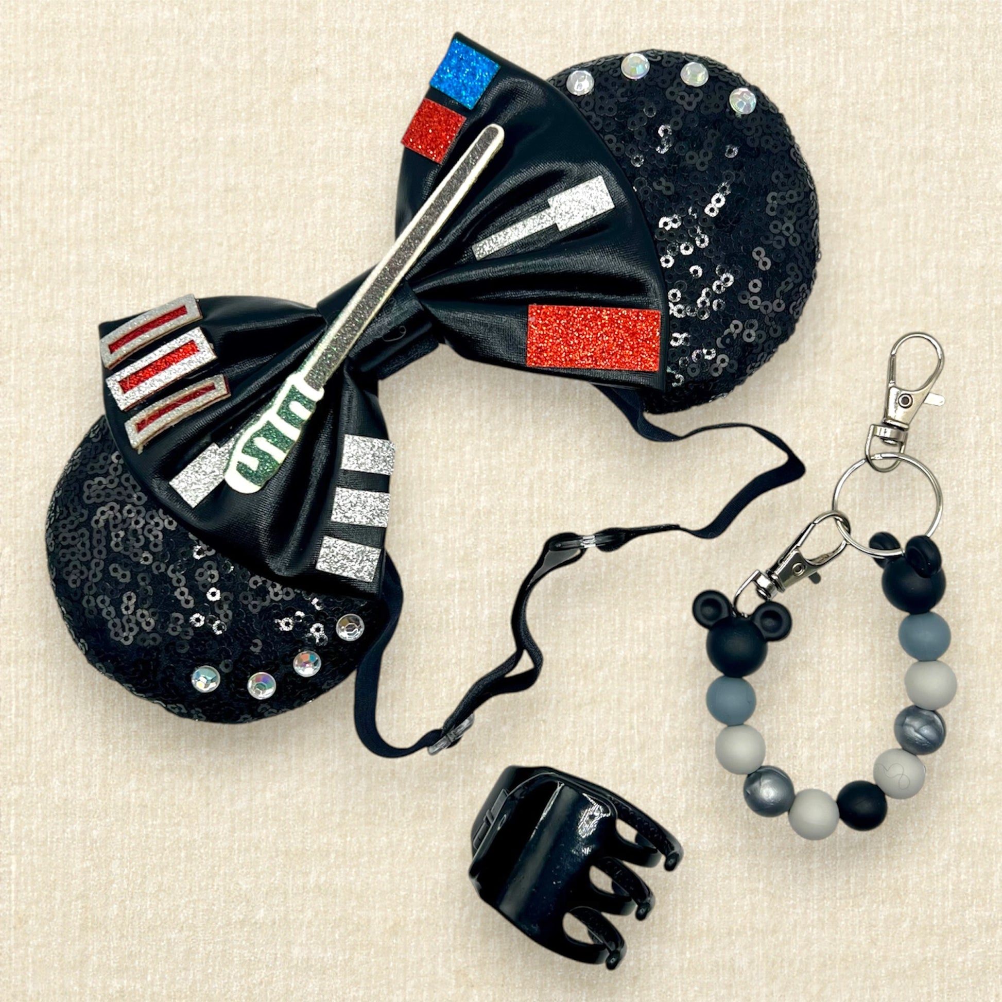 Black sequin mouse ears headband with metallic black bow, colorful glitter details, and rhinestones on an elastic headband; black claw clip; black and silver beaded mouse ears holder clip