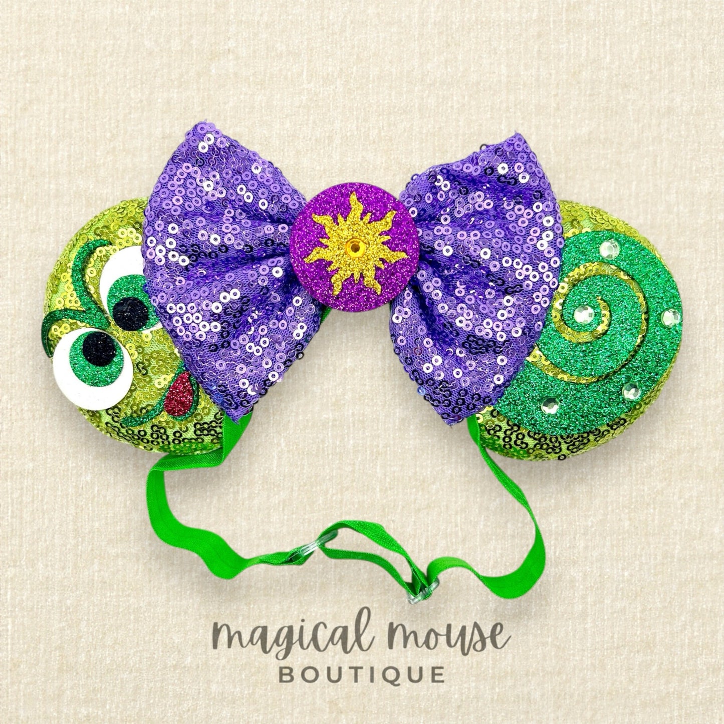 Decorative headband with purple sequin bow, green and yellow accents, and 'magical mouse boutique' text.