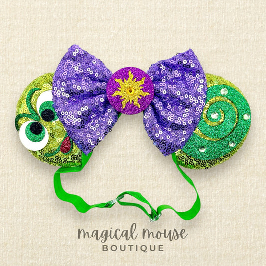 Decorative headband with purple sequin bow, green and yellow accents, and 'magical mouse boutique' text.