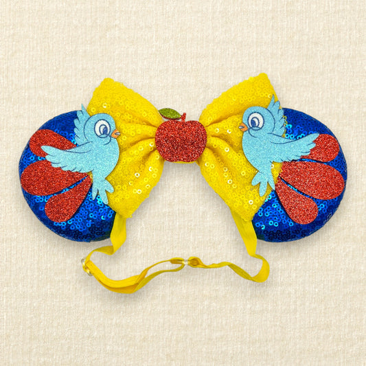 Blue sequin mouse ears with yellow bow, red glitter details, glitter bluebirds, and a red glitter apple centerpiece