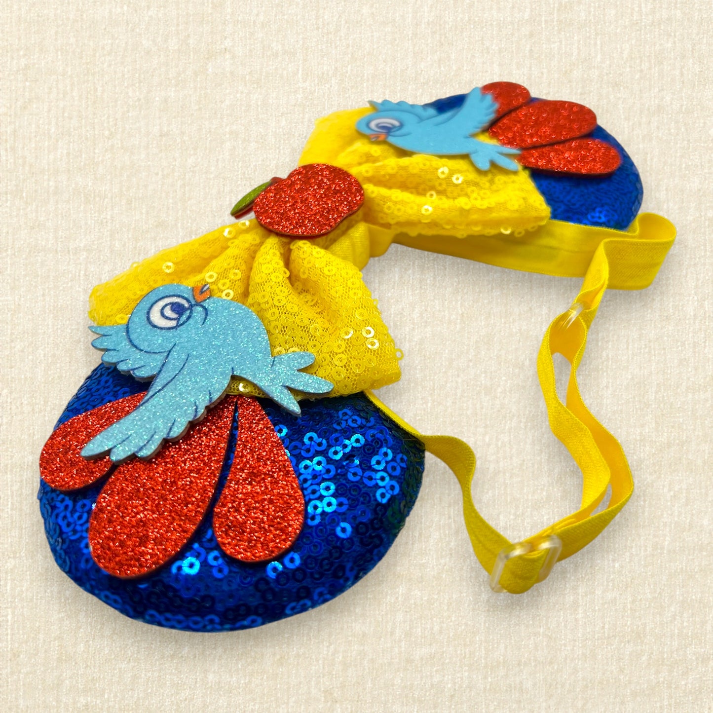 Blue sequin mouse ears with yellow bow, red glitter details, glitter bluebirds, and a red glitter apple centerpiece
