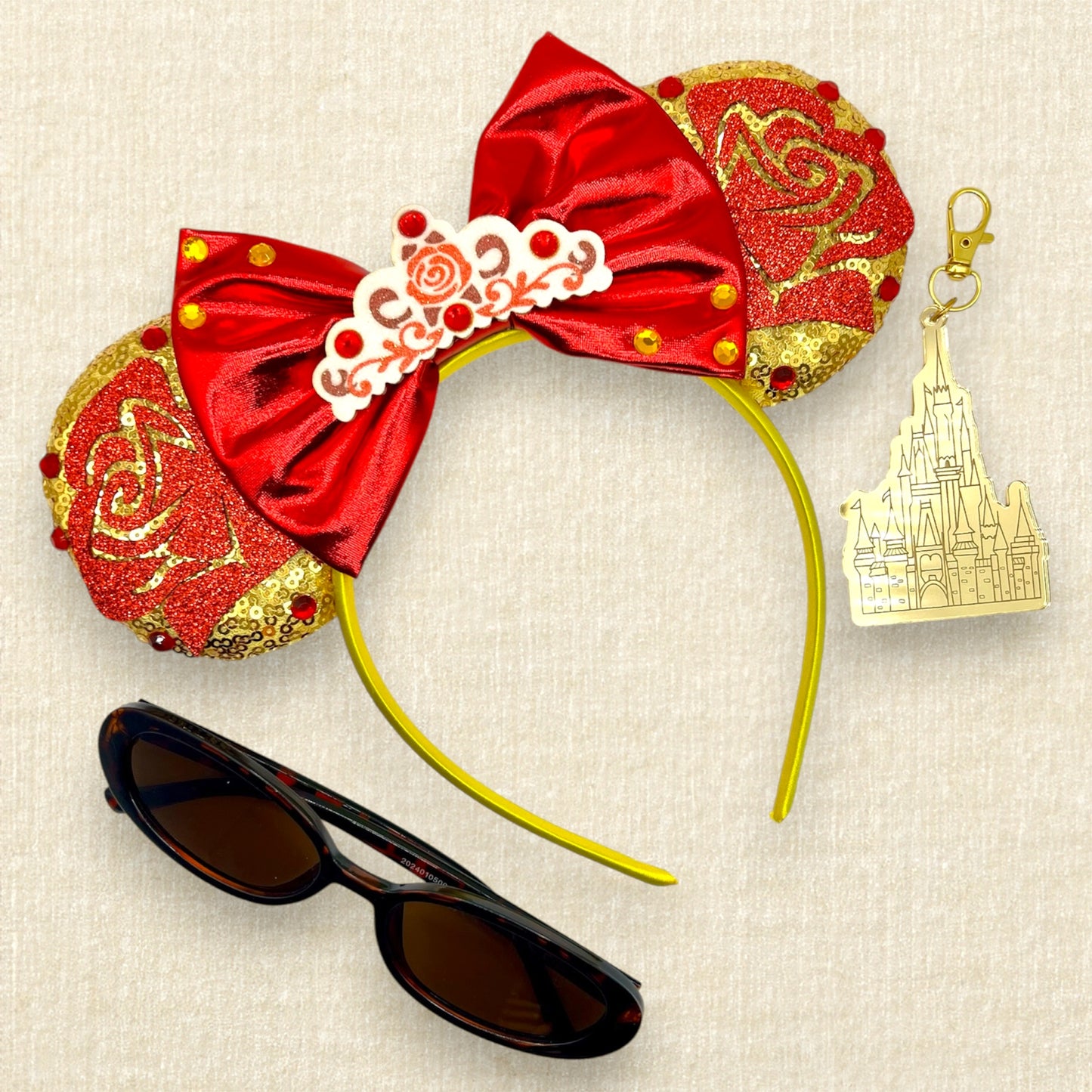 Gold mouse ears with red glitter roses, metallic red bow, glitter rose tiara, and rhinestones; sunglasses; gold castle keychain