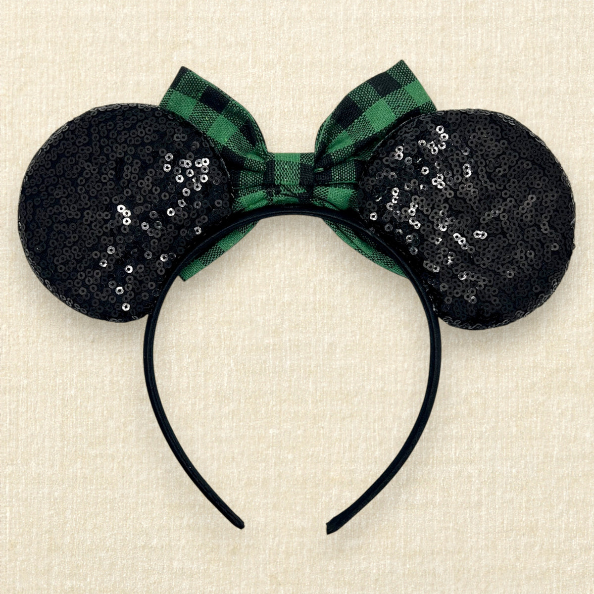 A festive Christmas-themed mouse ears headband with black sequin ears and a green and black buffalo plaid bow (back view)