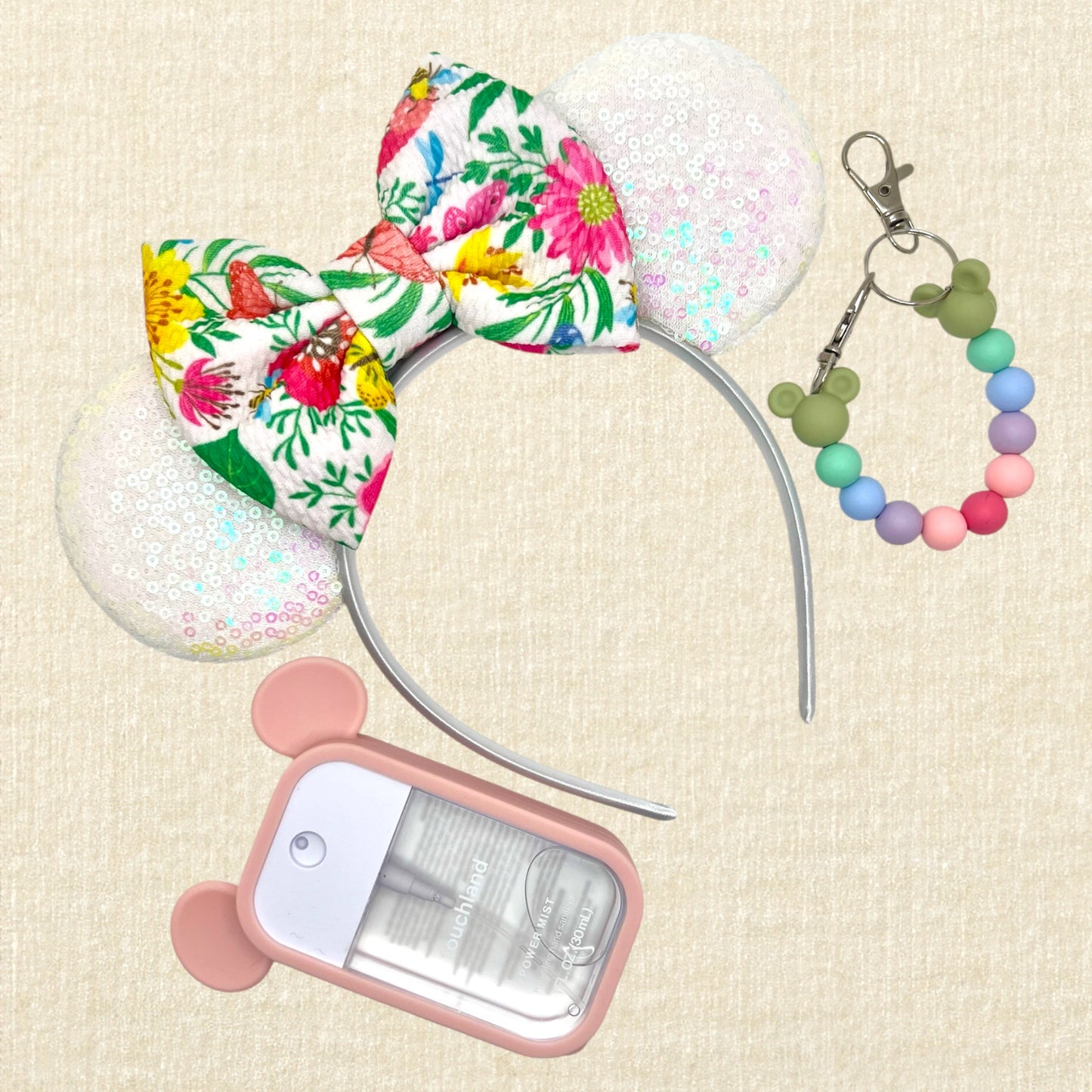Iridescent white mouse ears headband with colorful floral fabric bow; spray hand sanitizer in a pink mouse case; colorful beaded mouse ears holder keychain