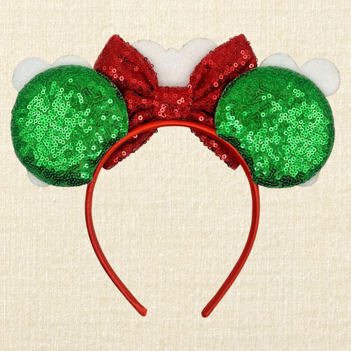 A festive Christmas-themed mouse ears headband featuring gingerbread mouse cookies, a red sequin bow, and a gingerbread house ornament, on a beige textured background (back view)