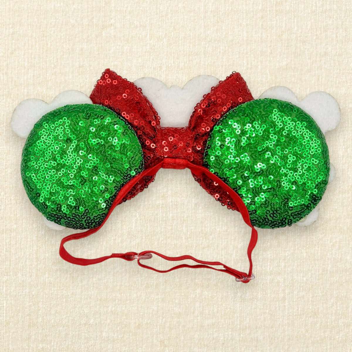 A festive Christmas mouse ears headband featuring green sequin ears with two gingerbread mouse cookies, a red sequin bow, and a gingerbread house in the center, with a red elastic headband (back view)