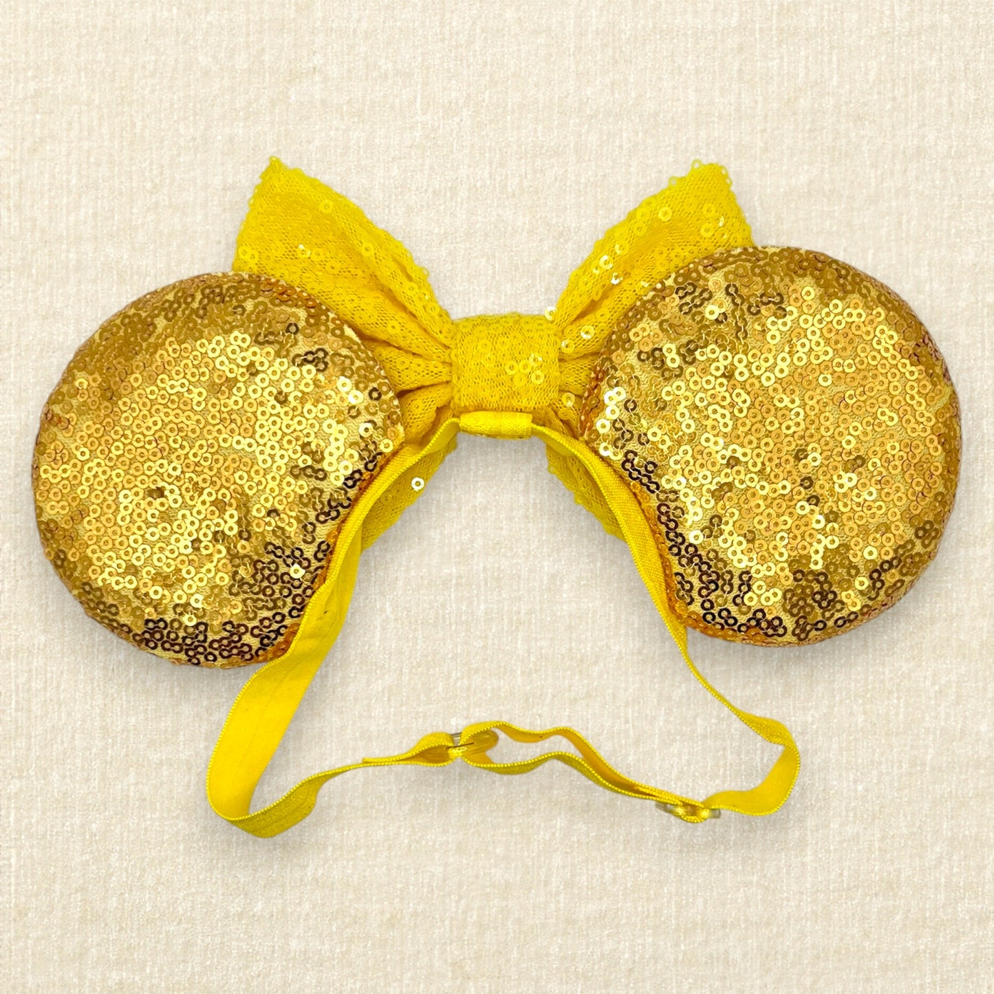 Gold sequin mouse ears with a yellow bow, silver tiara, and red roses on an elastic headband (back view)