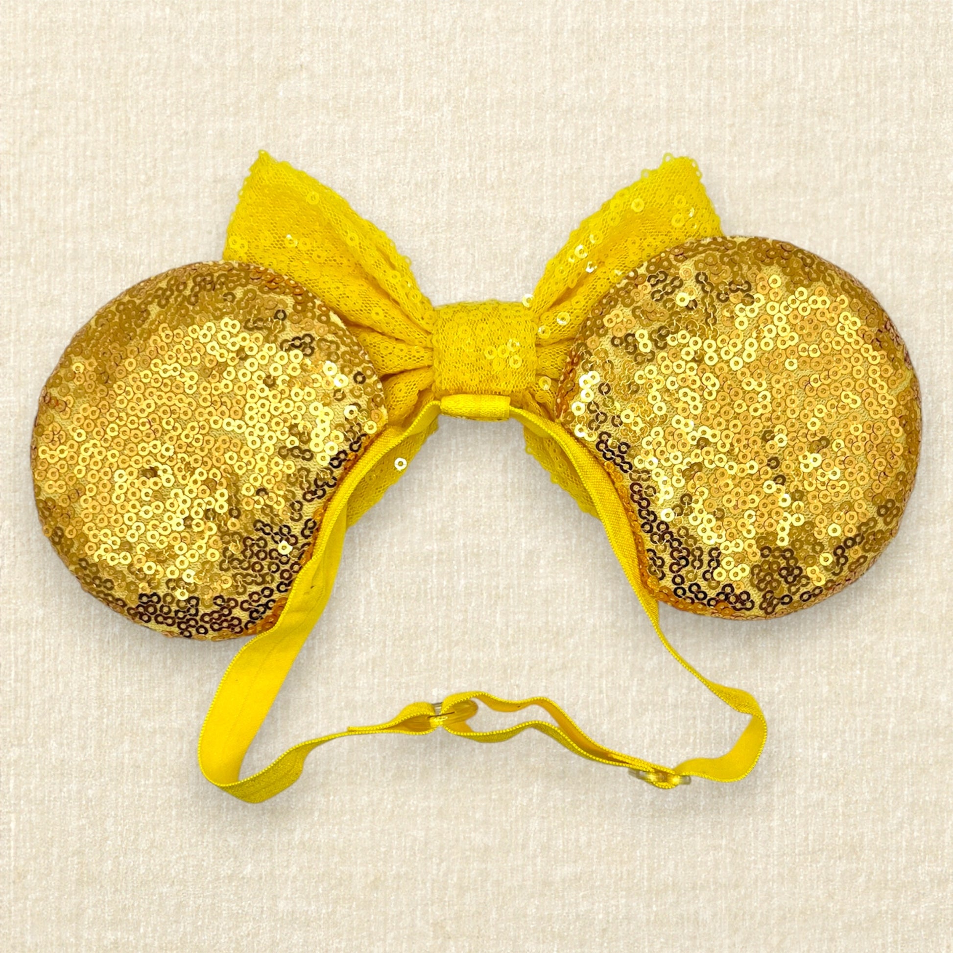 Gold sequin mouse ears with a yellow bow, silver tiara, and red roses on an elastic headband (back view)