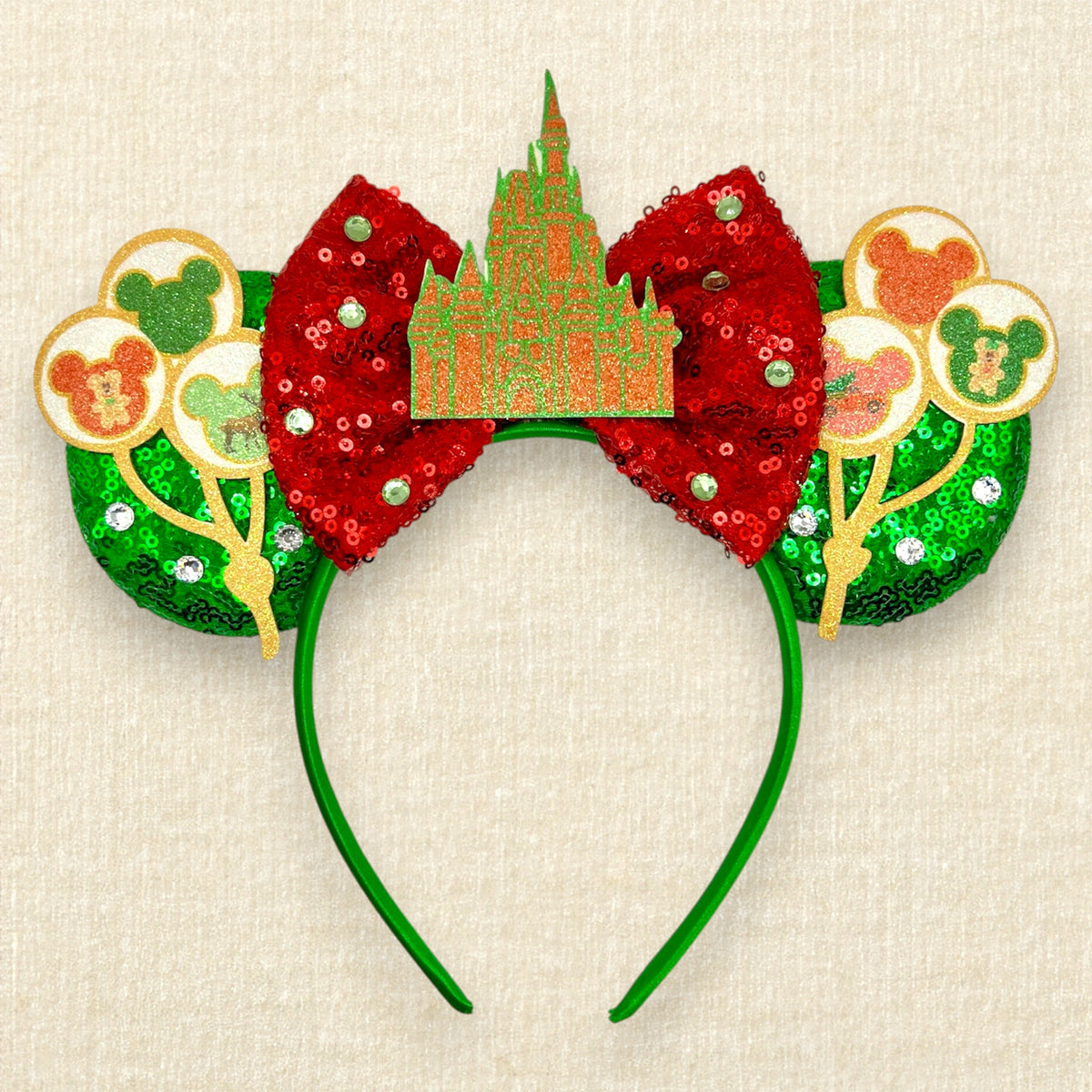 A Christmas-themed mouse ears headband with green sequin mouse ears, red sequin bow, and glitter red and green castle and holiday mouse balloon details.