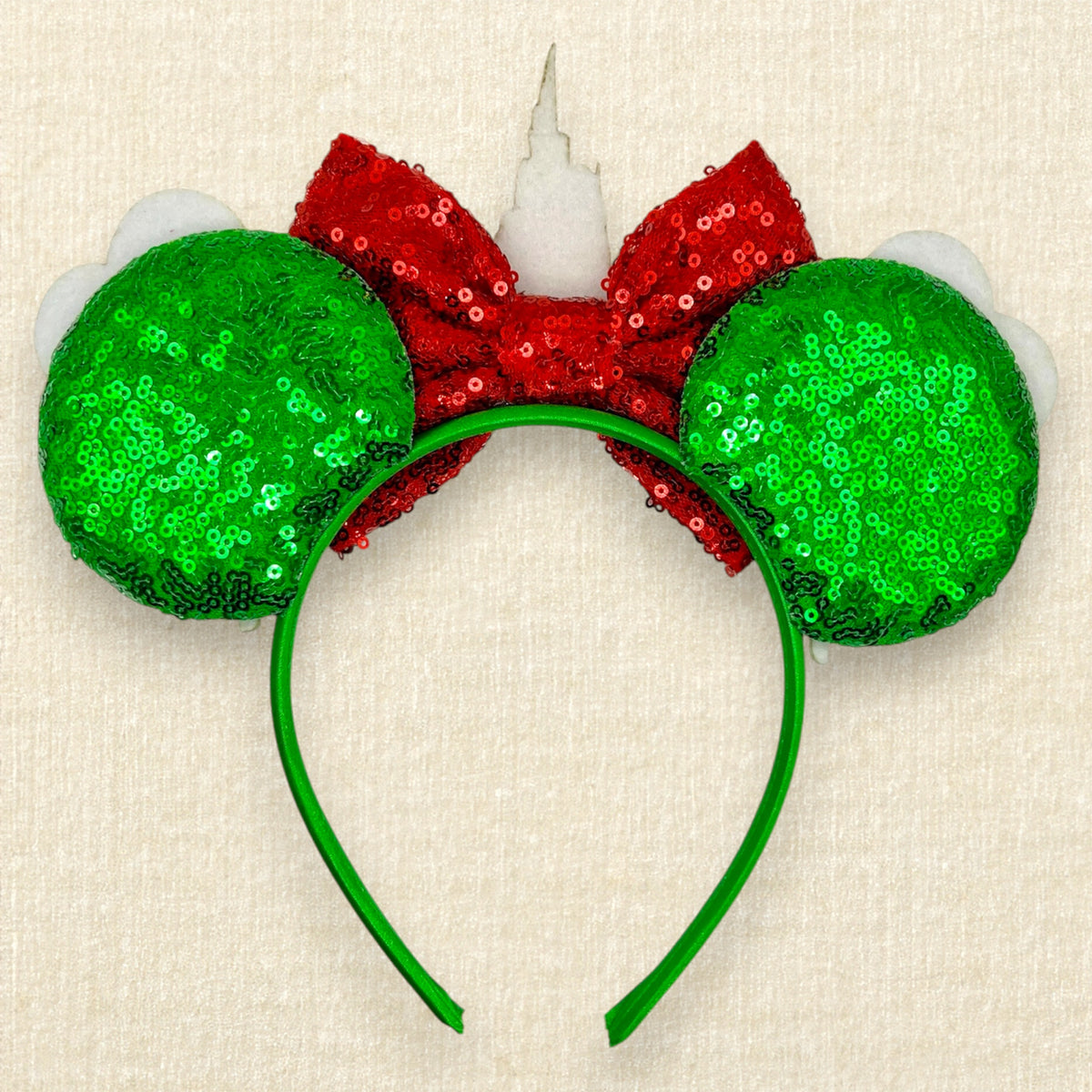 A Christmas-themed mouse ears headband with green sequin mouse ears, red sequin bow, and glitter red and green castle and holiday mouse balloon details (back view)