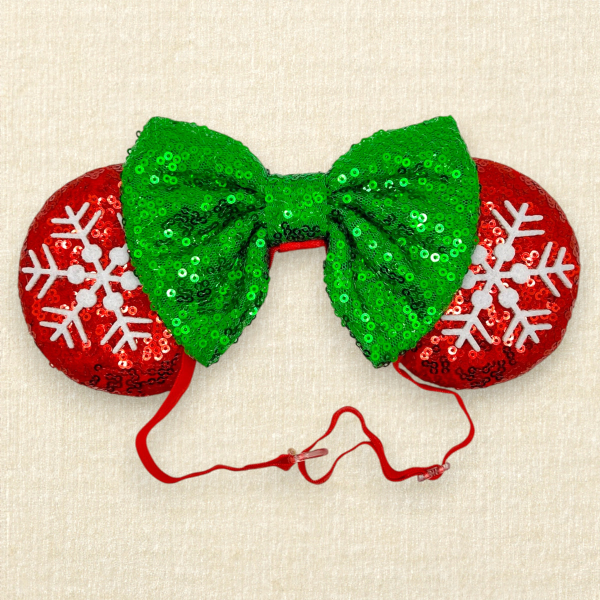 A festive Christmas mouse ears headband with red sequin mouse ears, white snowflake details, and a green sequin bow on an elastic headband