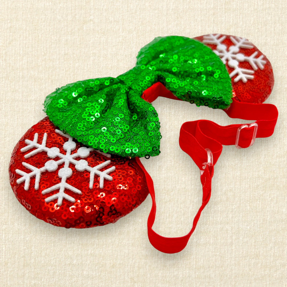 A festive Christmas mouse ears headband with red sequin mouse ears, white snowflake details, and a green sequin bow on an elastic headband